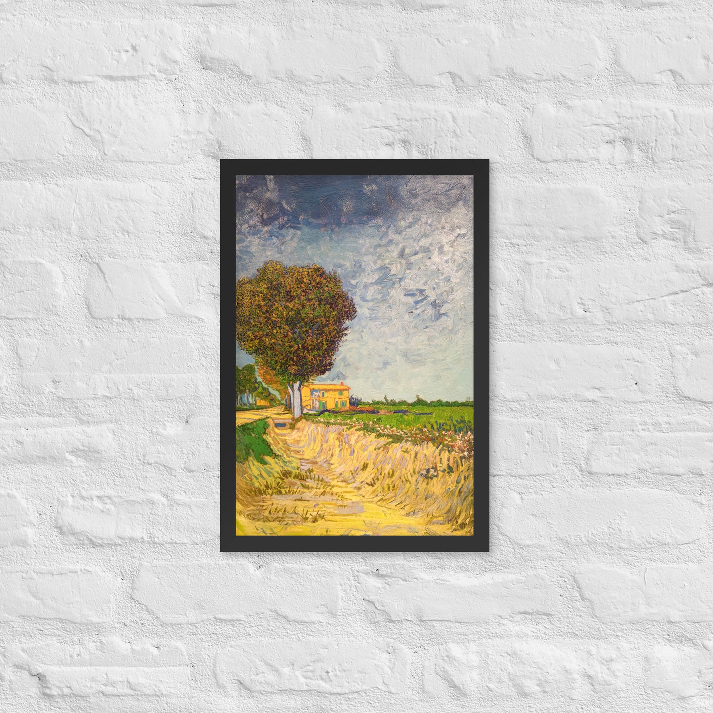 Van Gogh's 'A Lane near Arles' on a 12"x18" black framed poster print on a white brick wall.