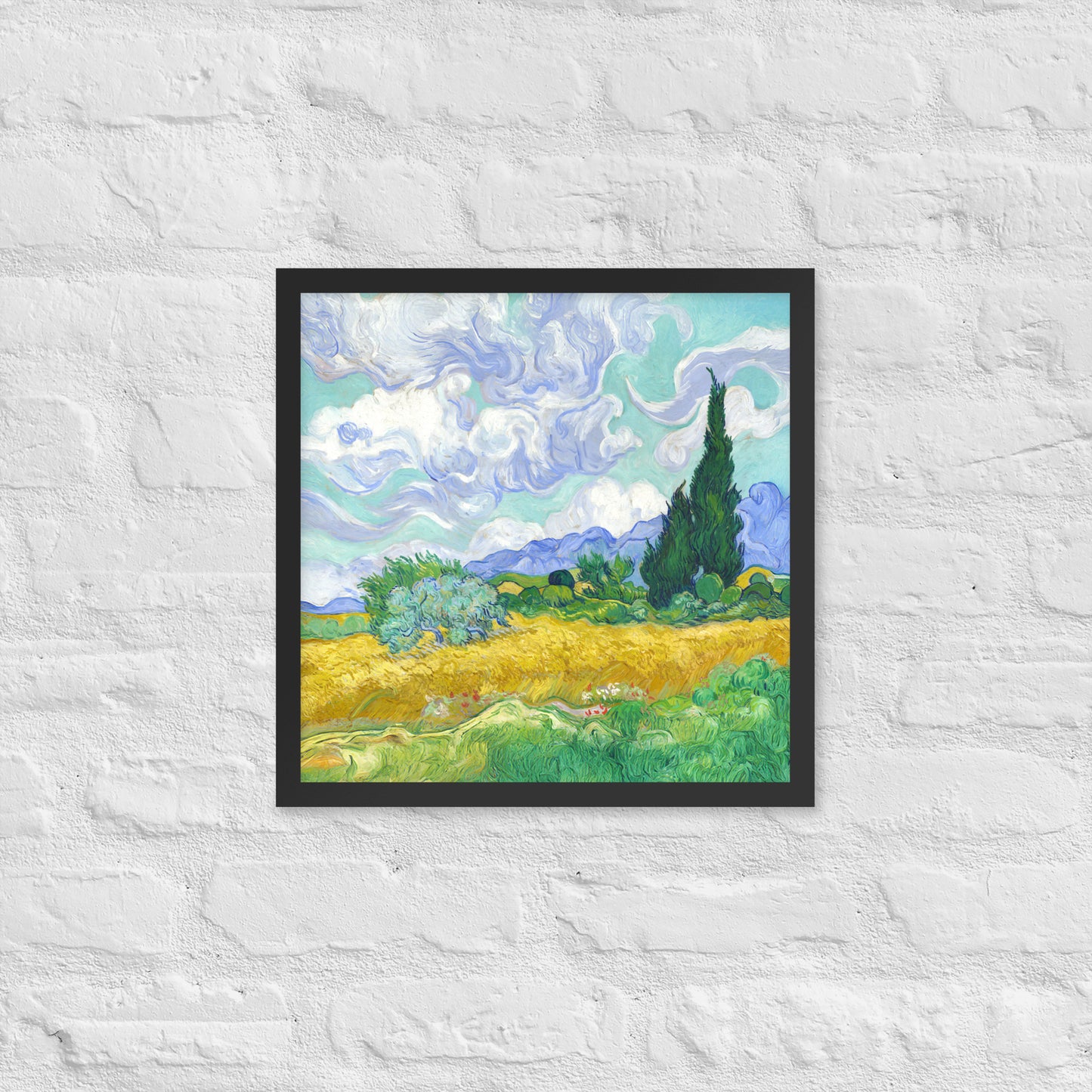 Van Gogh's 'Wheat Field with Cypresses' on a 16"x16" black framed poster print on a white brick wall.