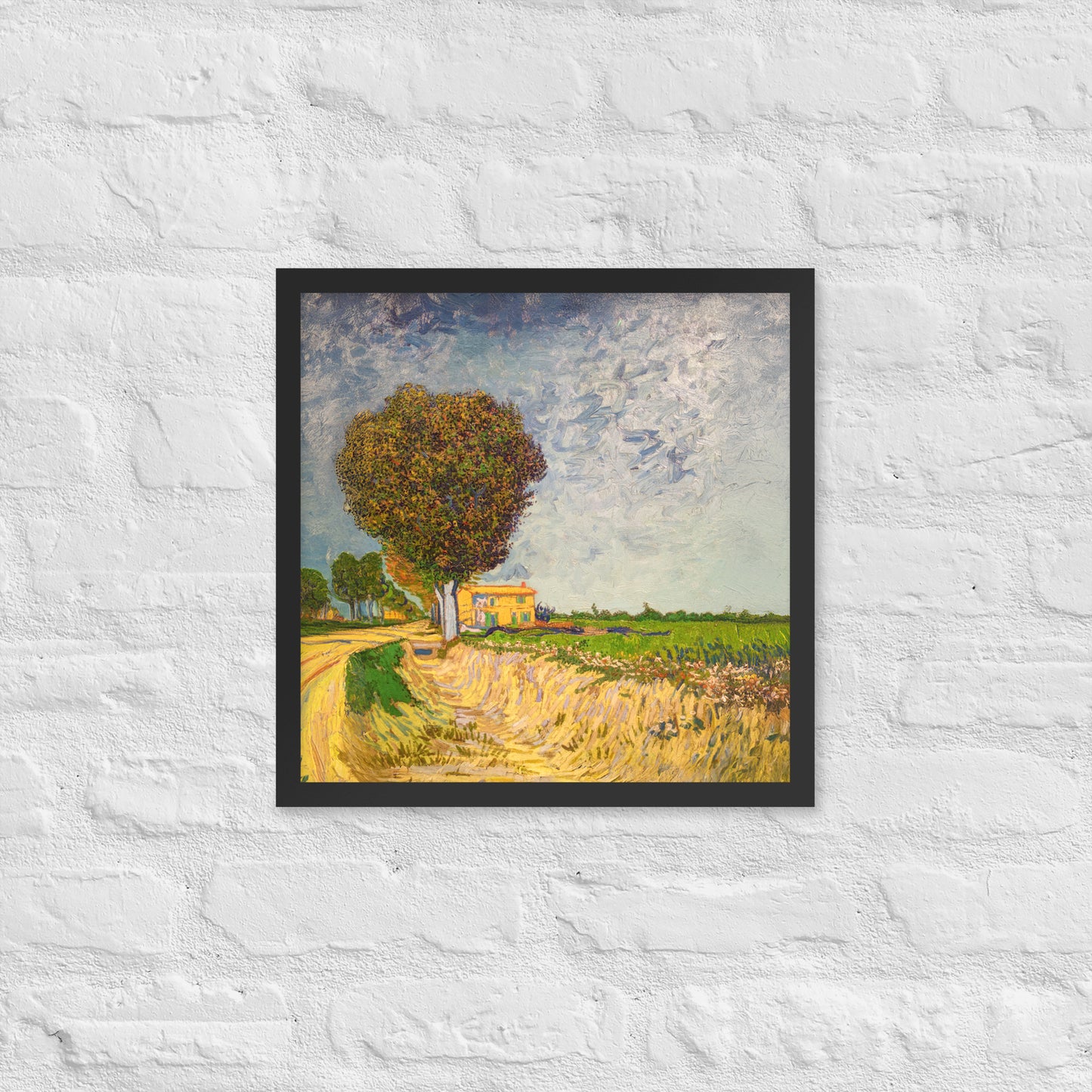 Van Gogh's 'A Lane near Arles' on a 16"x16" black framed poster print on a white brick wall.