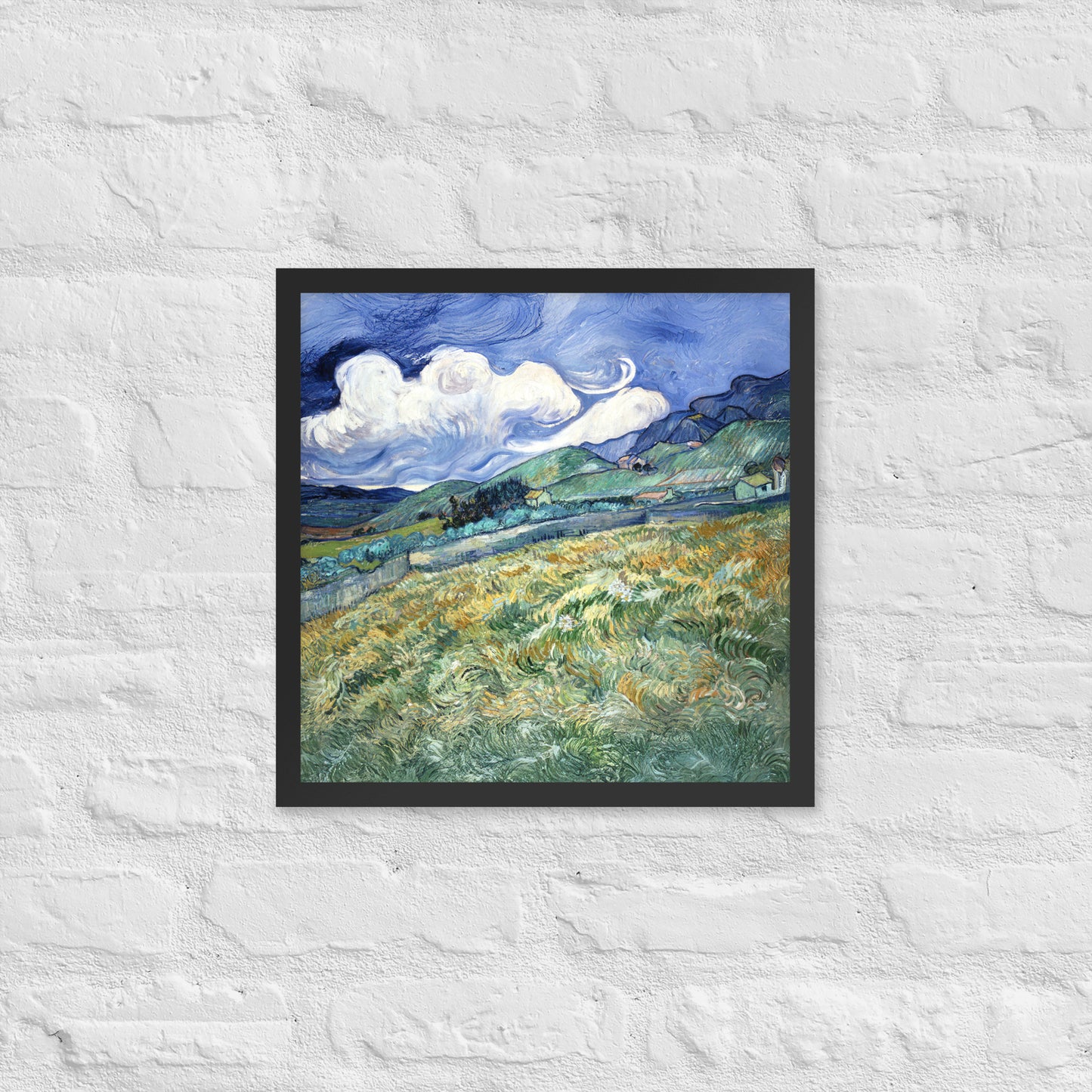 Van Gogh's 'Landscape from Saint-Rémy' on a 16"x16" black framed poster print on a white brick wall.