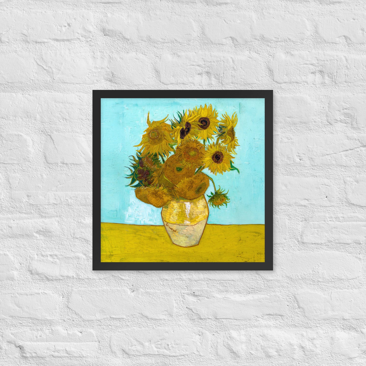 Van Gogh's 'Vase with Twelve Sunflowers' on a 16"x16" black framed poster print on a white brick wall.