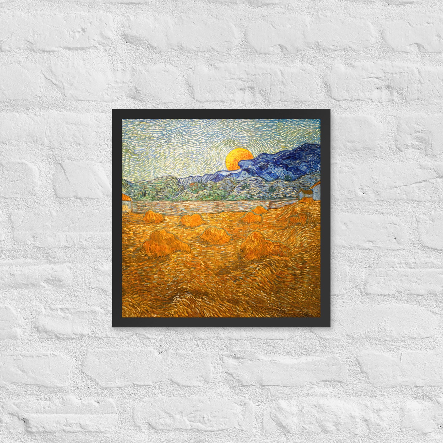 Van Gogh's 'Landscape with Wheat Sheaves and Rising Moon' on a 16"x16" black framed poster print on a white brick wall.
