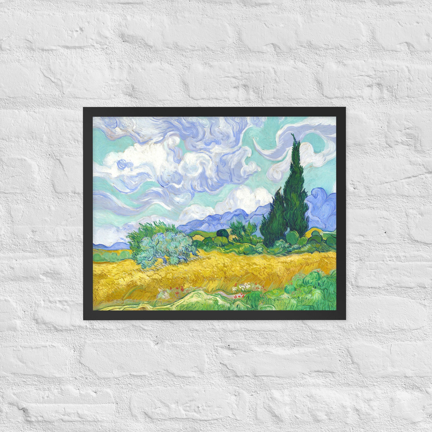 Van Gogh's 'Wheat Field with Cypresses' on a 16"x20" black framed poster print on a white brick wall.