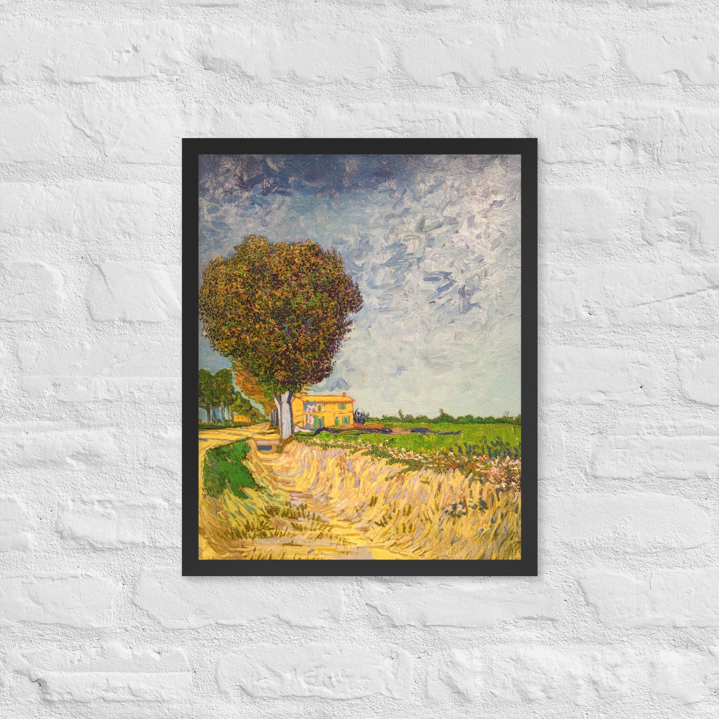Van Gogh's 'A Lane near Arles' on a 16"x20" black framed poster print on a white brick wall.
