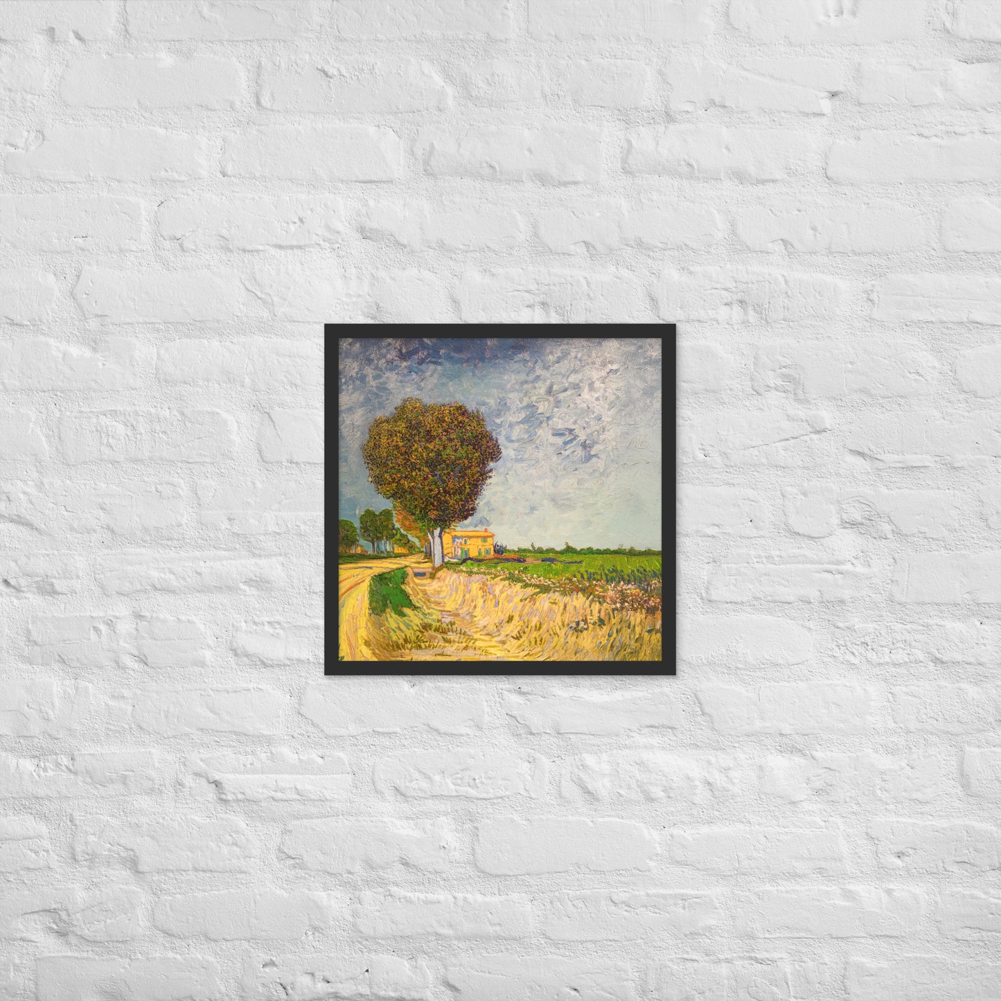 Van Gogh's 'A Lane near Arles' on a 18"x18" black framed poster print on a white brick wall.