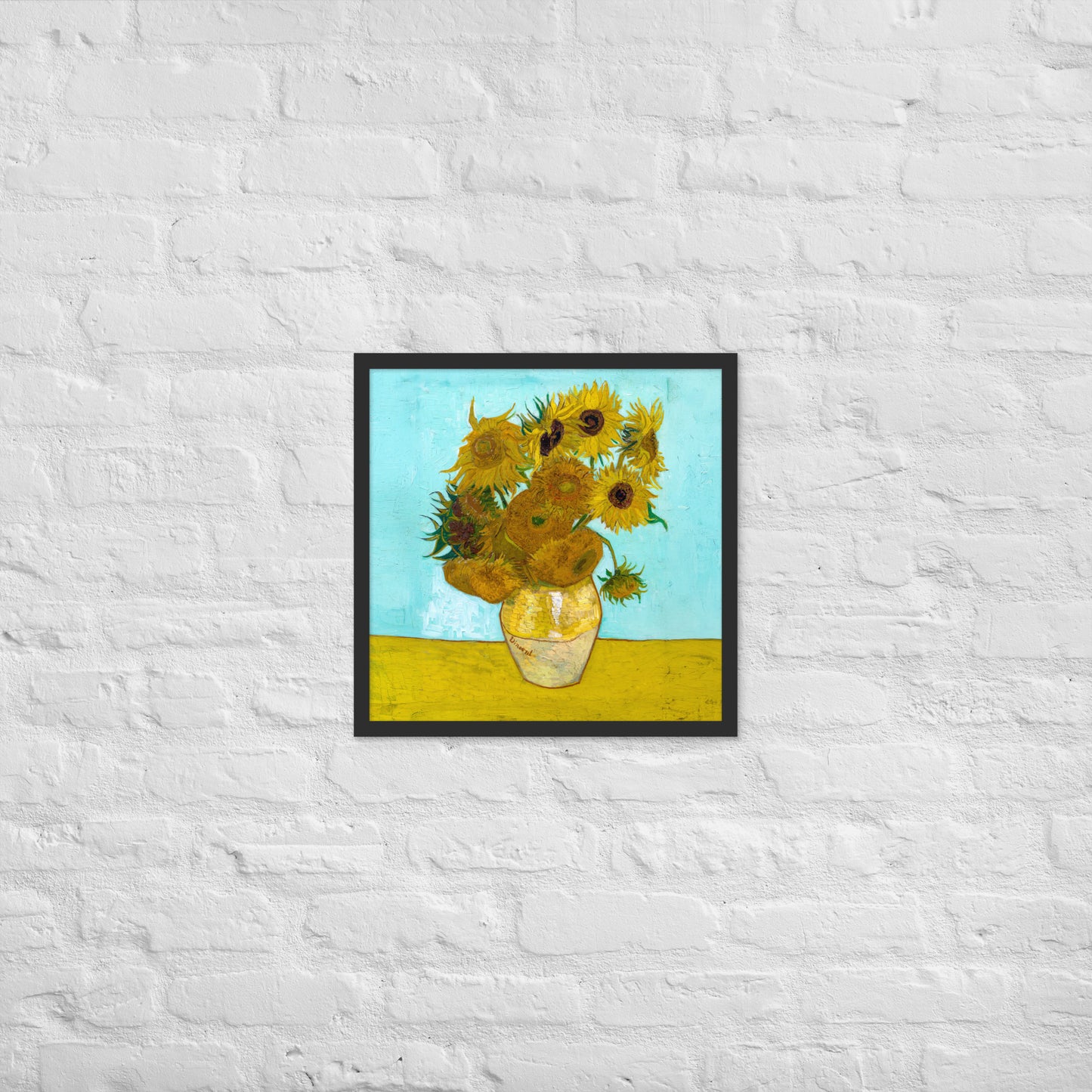 Van Gogh's 'Vase with Twelve Sunflowers' on a 18"x18" black framed poster print on a white brick wall.