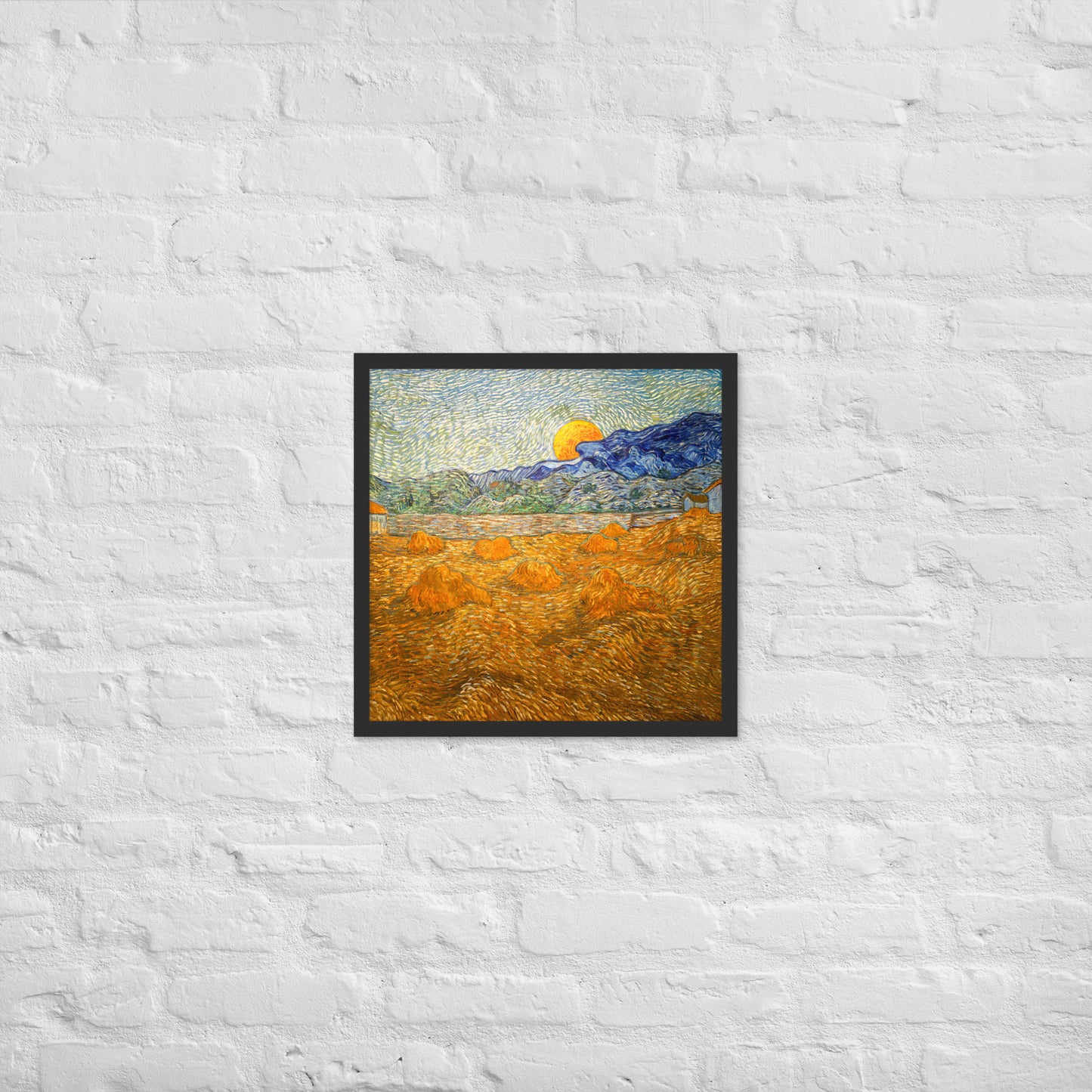 Van Gogh's 'Landscape with Wheat Sheaves and Rising Moon' on a 18"x18" black framed poster print on a white brick wall.