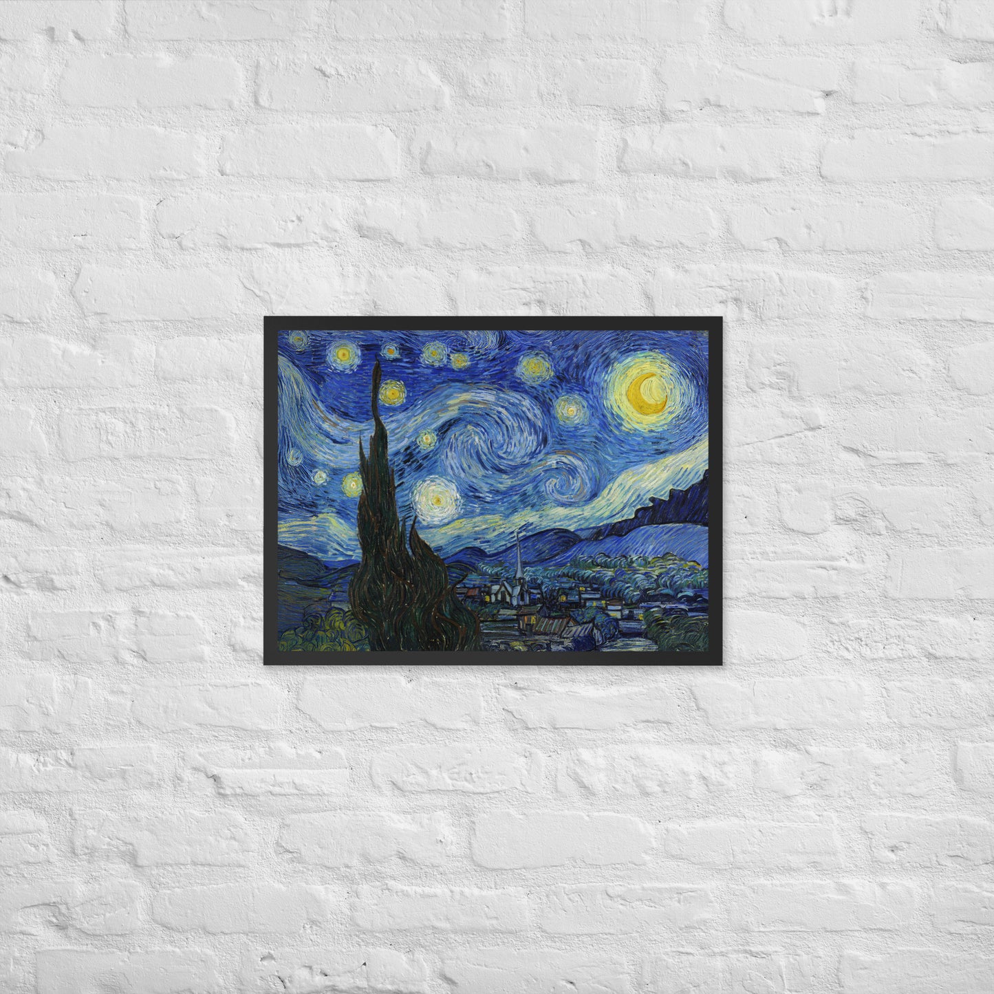 Van Gogh's 'Starry Night' on a 18"x24" black framed poster print on a white brick wall.