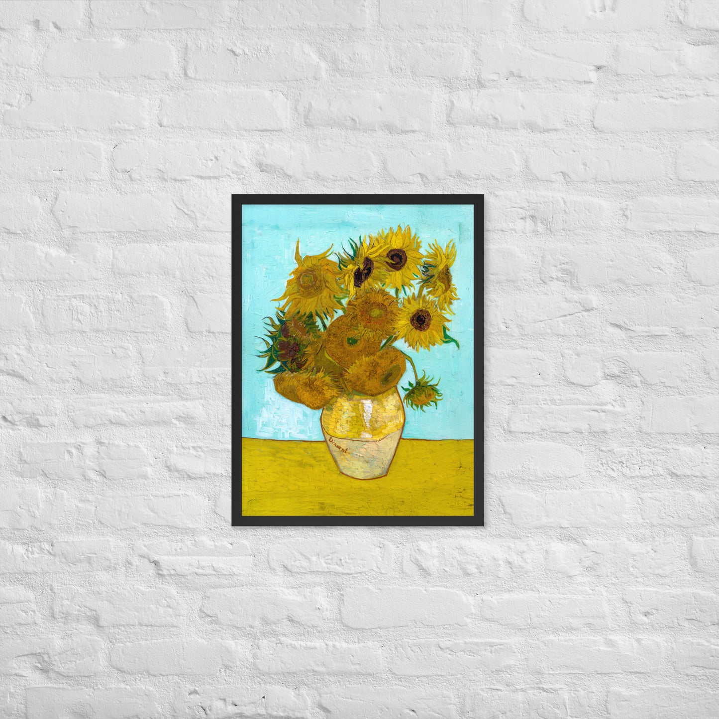 Van Gogh's 'Vase with Twelve Sunflowers' on a 18"x24" black framed poster print on a white brick wall.