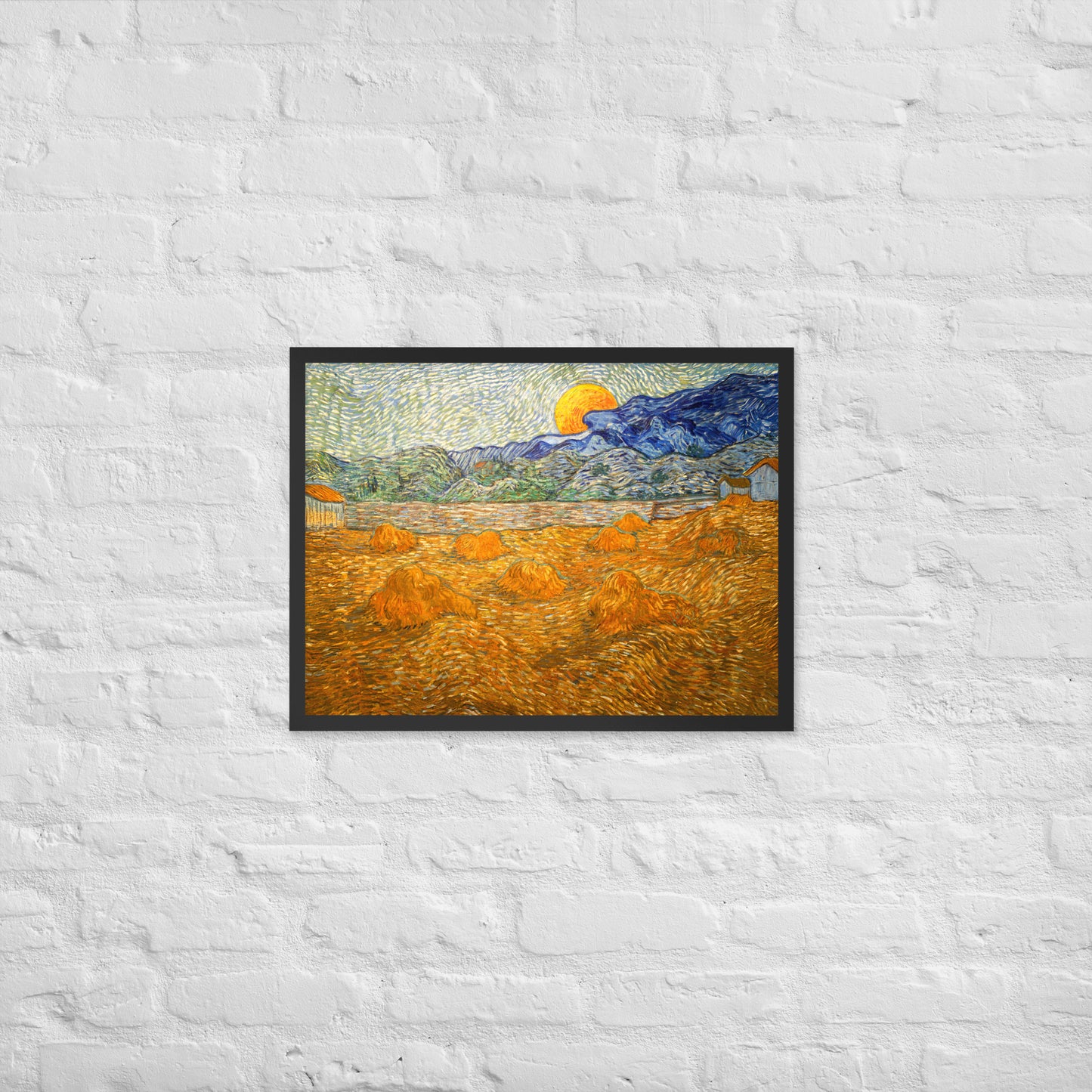 Van Gogh's 'Landscape with Wheat Sheaves and Rising Moon' on a 18"x24" black framed poster print on a white brick wall.