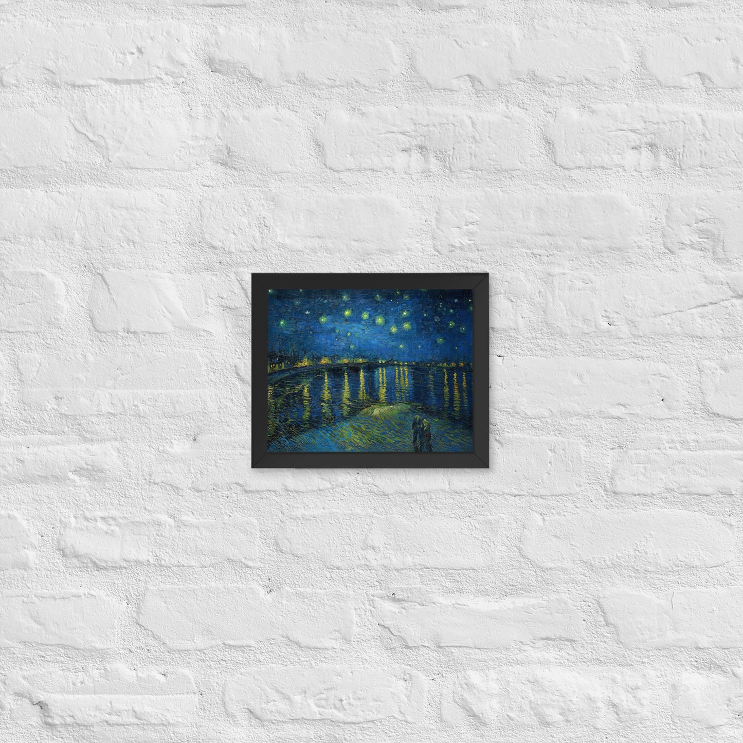 Van Gogh's 'Starry Night Over the Rhone' on a 8"x10" black framed poster print on a white brick wall.
