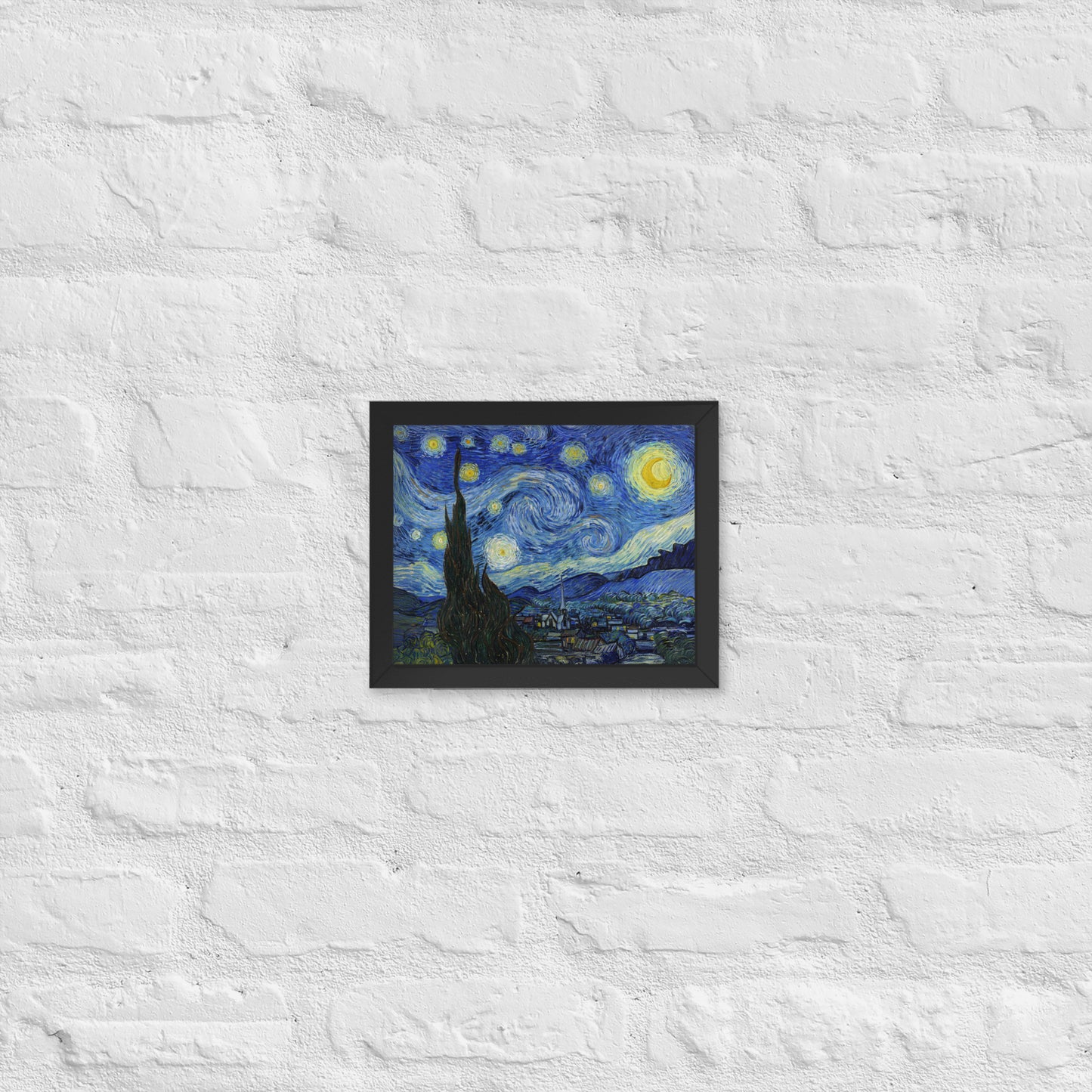 Van Gogh's 'Starry Night' on a 8"x10" black framed poster print on a white brick wall.