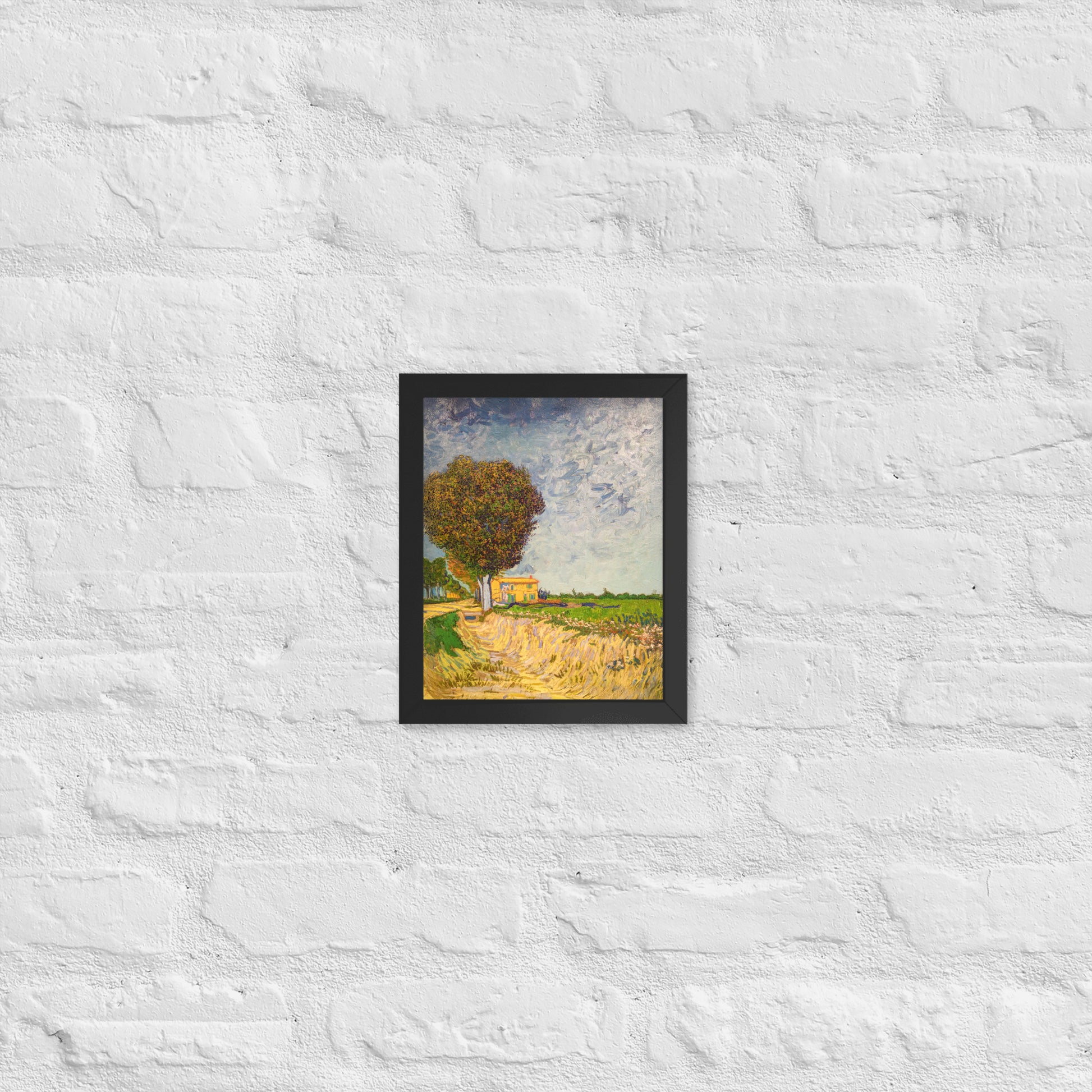Van Gogh's 'A Lane near Arles' on a 8"x10" black framed poster print on a white brick wall.