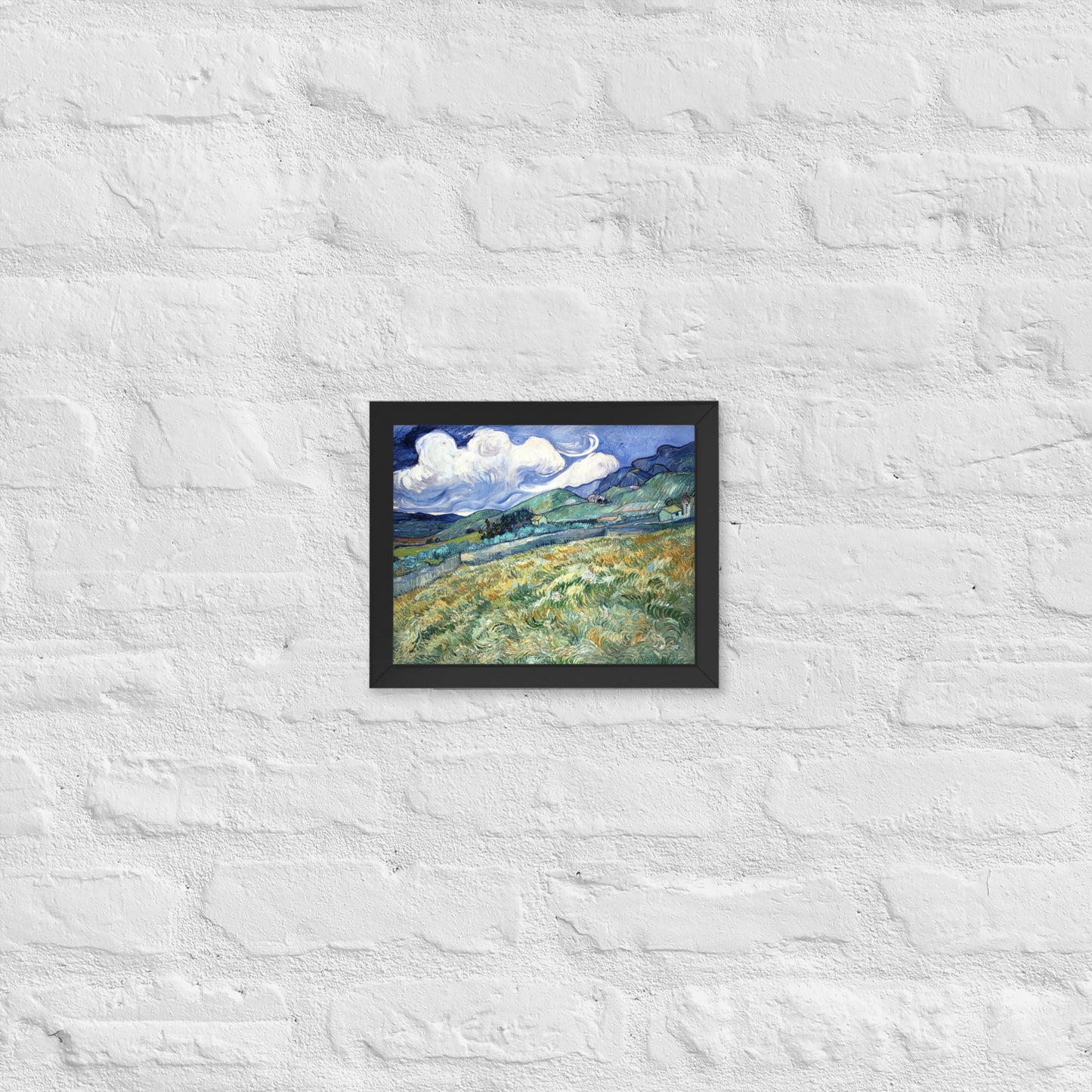 Van Gogh's 'Landscape from Saint-Rémy' on a 8"x10" black framed poster print on a white brick wall.