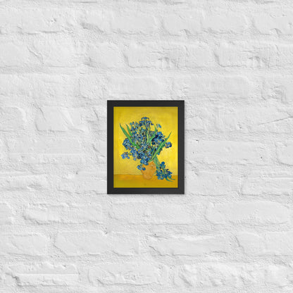 Van Gogh's 'Vase with Irises Against a Yellow Background' on a 8"x10" black framed poster print on a white brick wall.