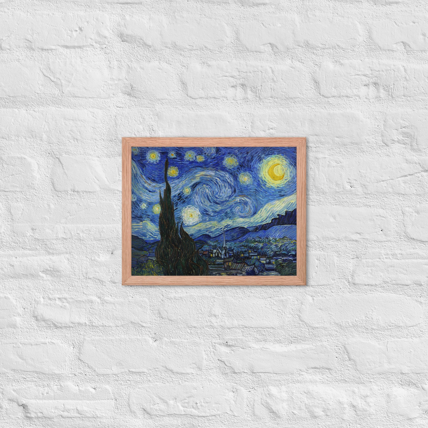 Van Gogh's 'Starry Night' on a 11"x14" red oak framed poster print on a white brick wall.