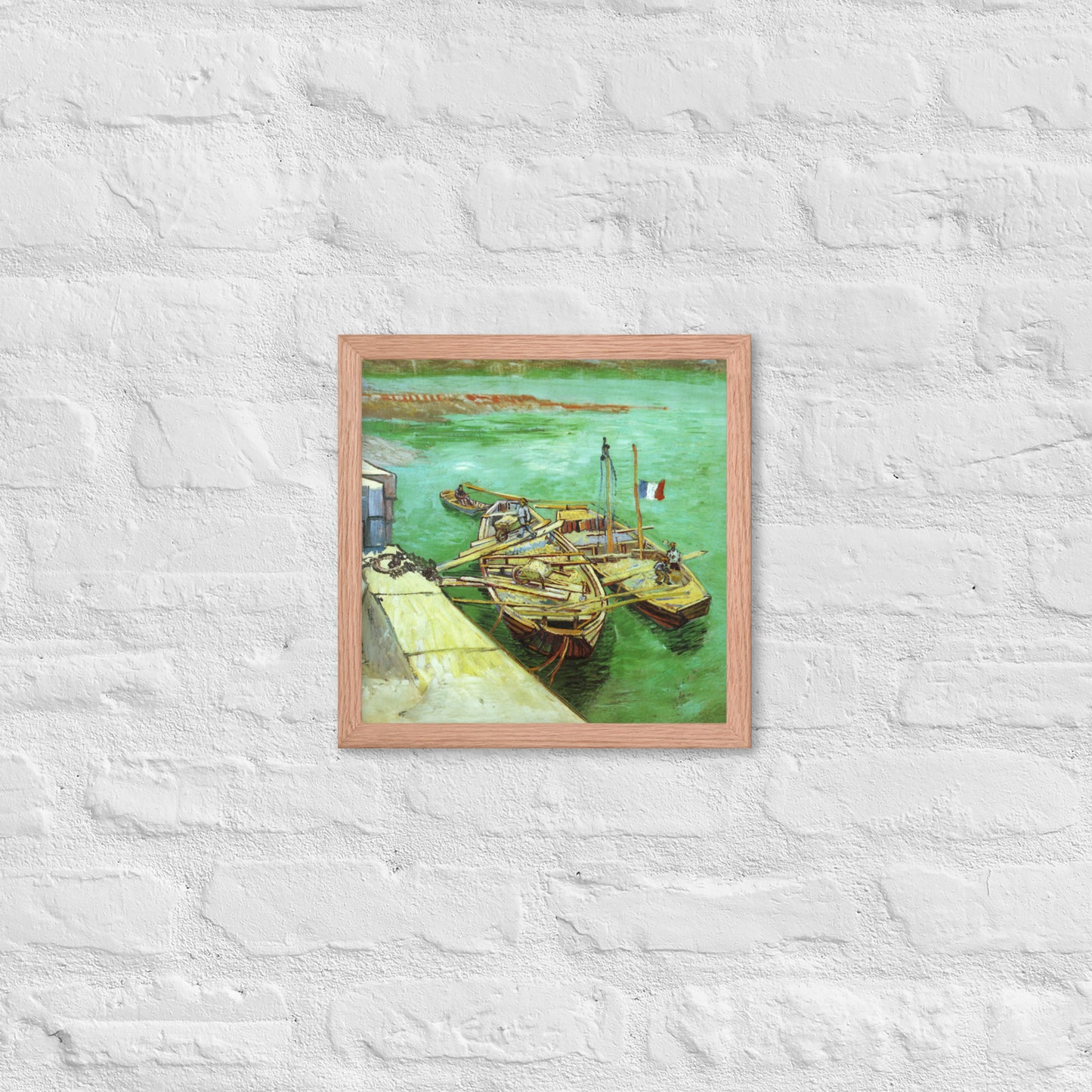 Van Gogh's 'Quay with Men Unloading Sand Barges' on a 12"x12" red oak framed poster print on a white brick wall.