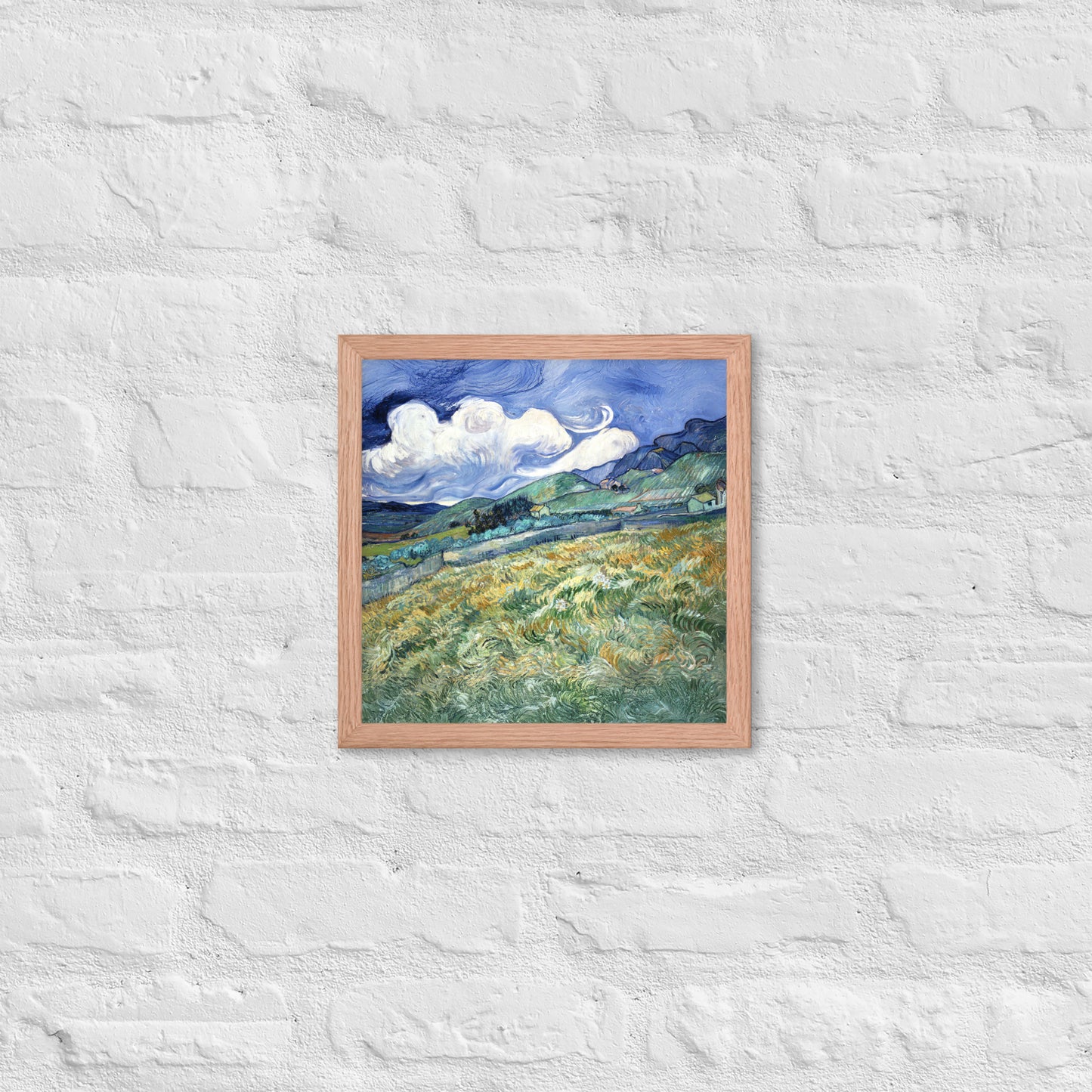 Van Gogh's 'Landscape from Saint-Rémy' on a 12"x12" red oak framed poster print on a white brick wall.