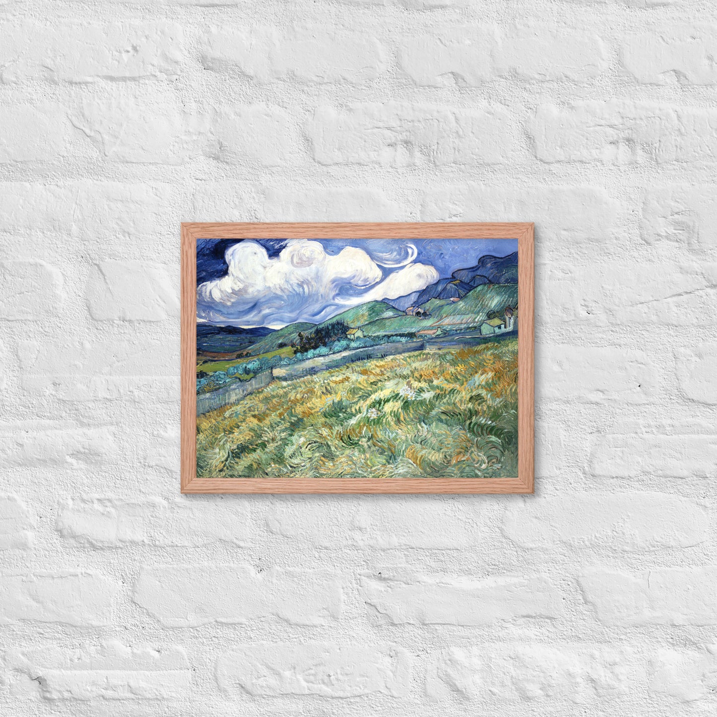 Van Gogh's 'Landscape from Saint-Rémy' on a 12"x16" red oak framed poster print on a white brick wall.