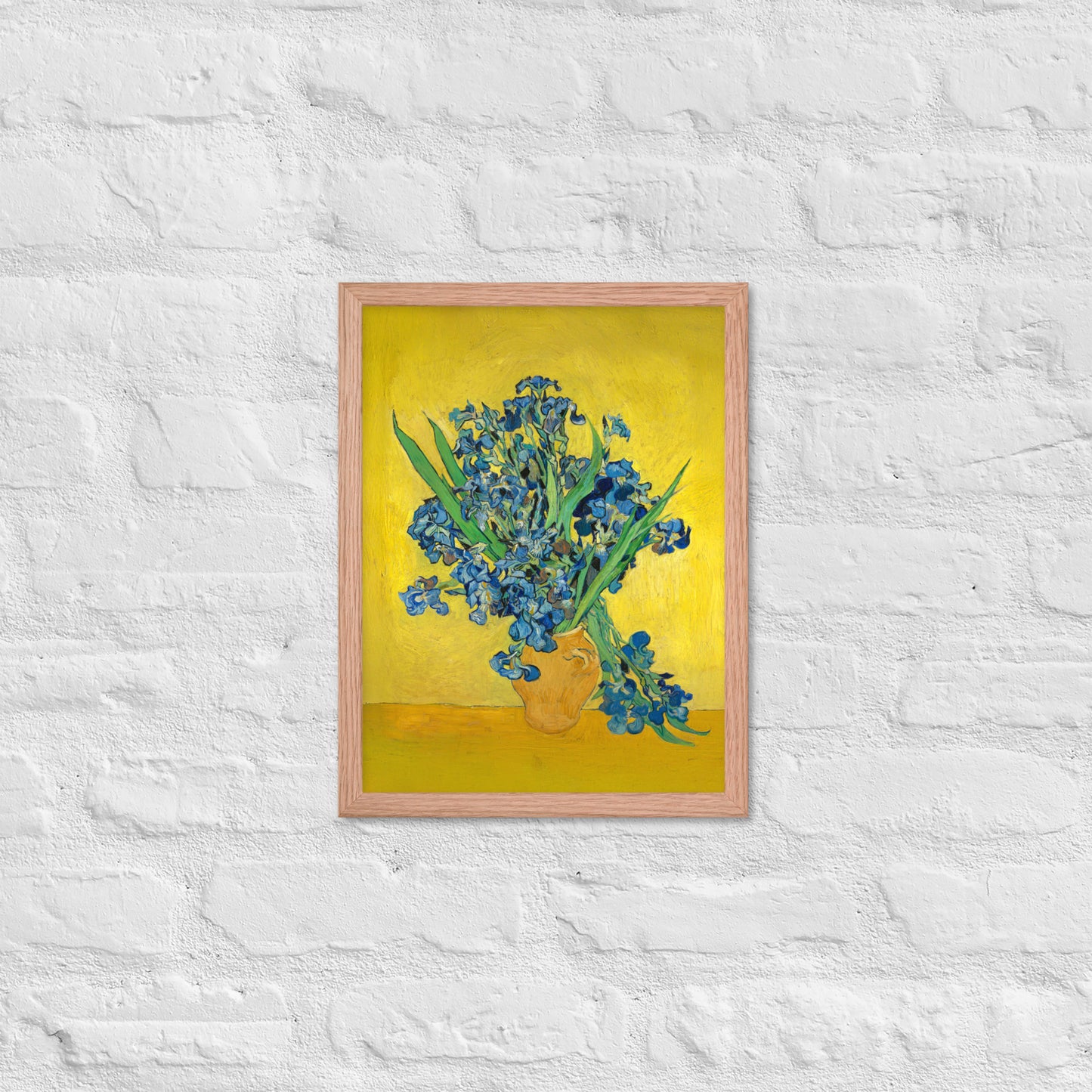 Van Gogh's 'Vase with Irises Against a Yellow Background' on a 12"x16" red oak framed poster print on a white brick wall.