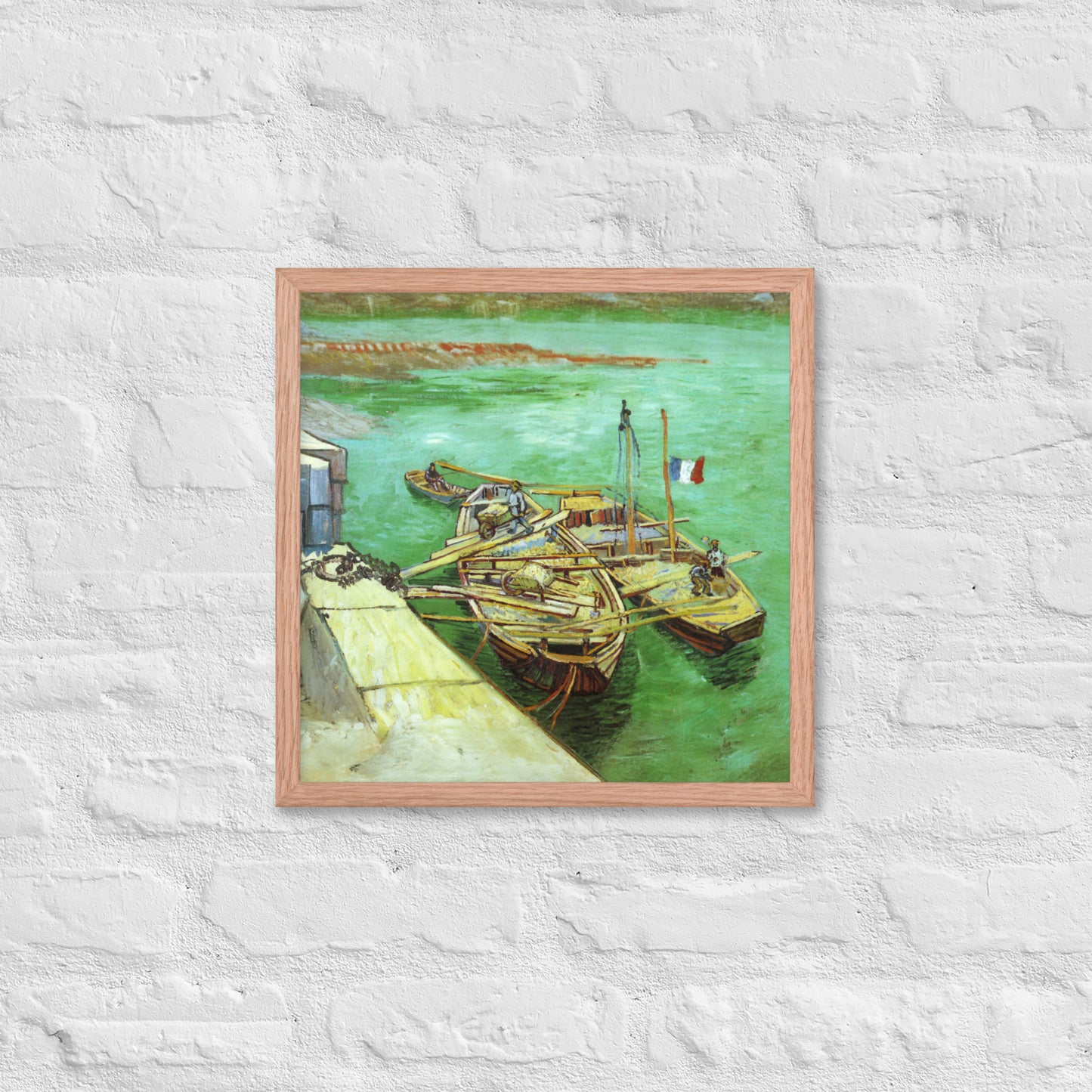 Van Gogh's 'Quay with Men Unloading Sand Barges' on a 16"x16" red oak framed poster print on a white brick wall.