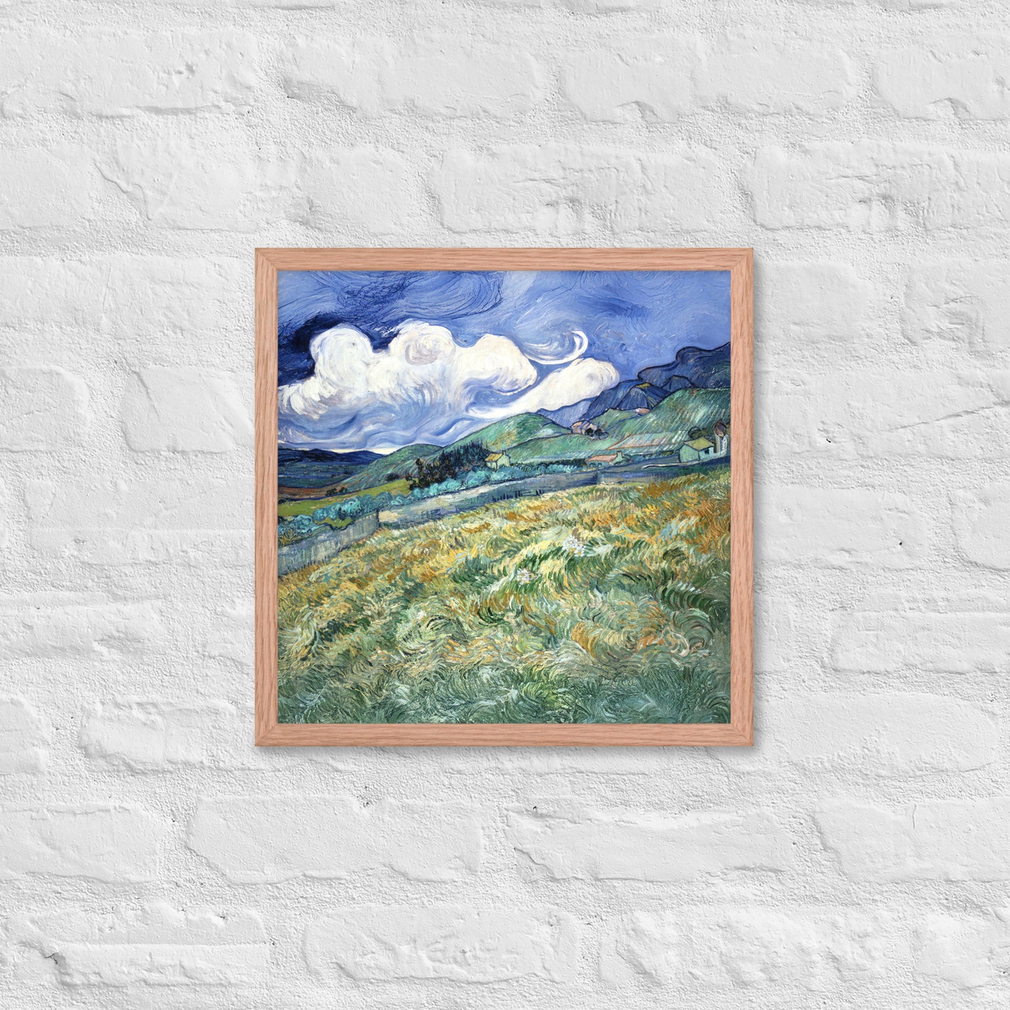 Van Gogh's 'Landscape from Saint-Rémy' on a 16"x16" red oak framed poster print on a white brick wall.