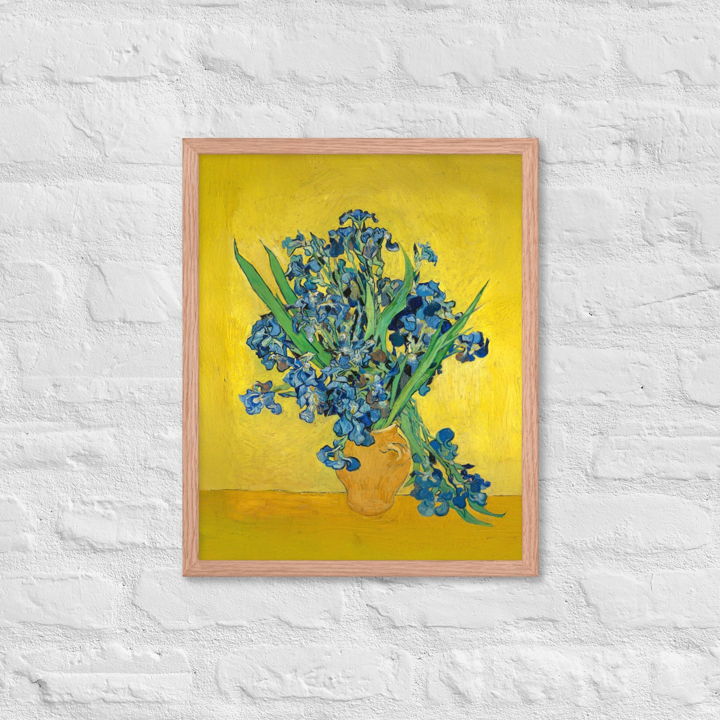 Van Gogh's 'Vase with Irises Against a Yellow Background' on a 16"x20" red oak framed poster print on a white brick wall.