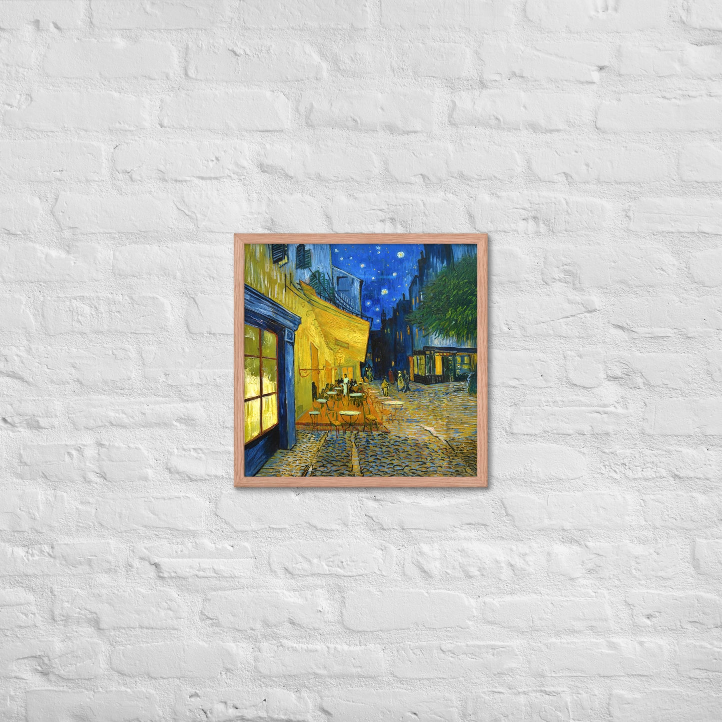 Van Gogh's 'Café Terrace at Night' on a 18"x18" red oak framed poster print on a white brick wall.
