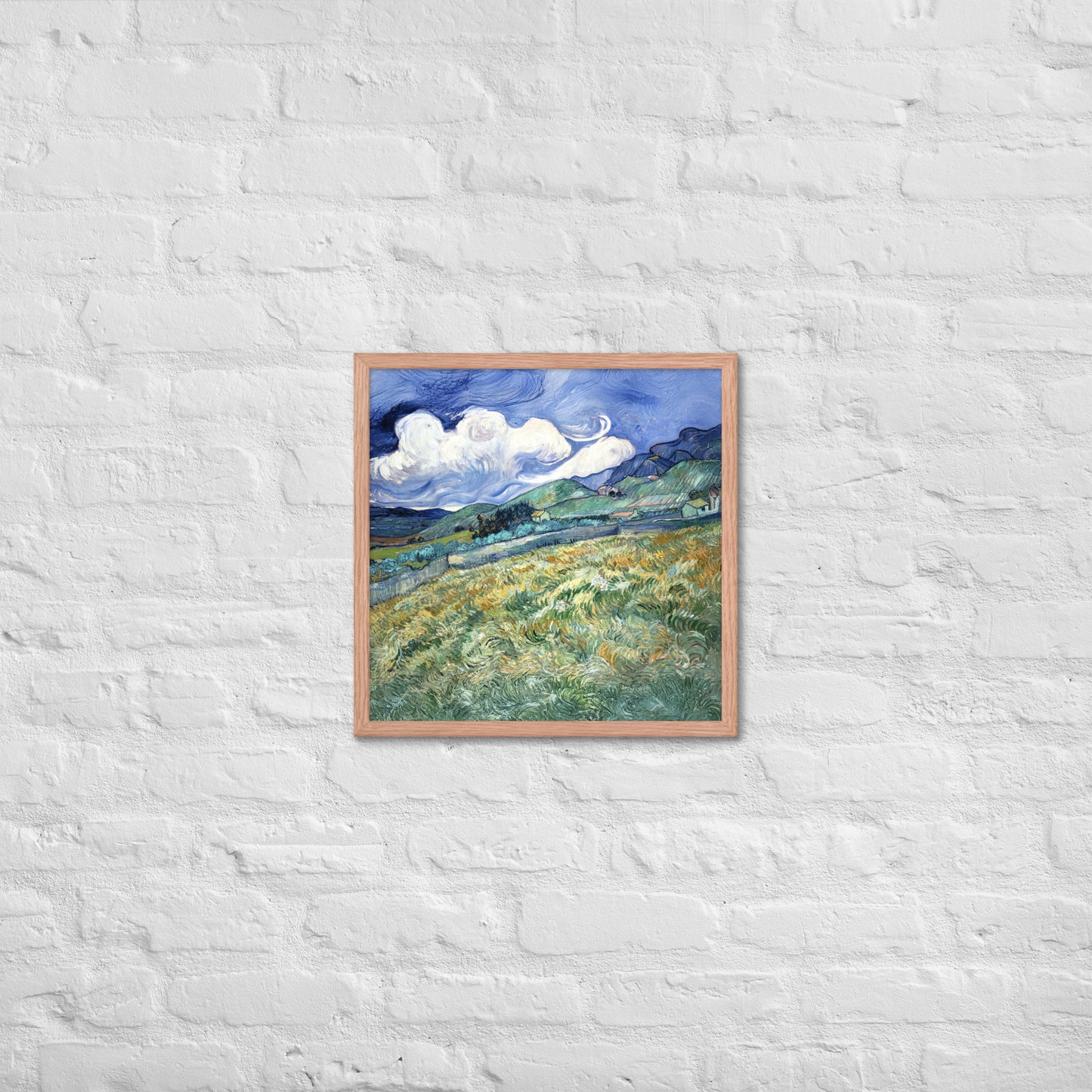 Van Gogh's 'Landscape from Saint-Rémy' on a 18"x18" red oak framed poster print on a white brick wall.