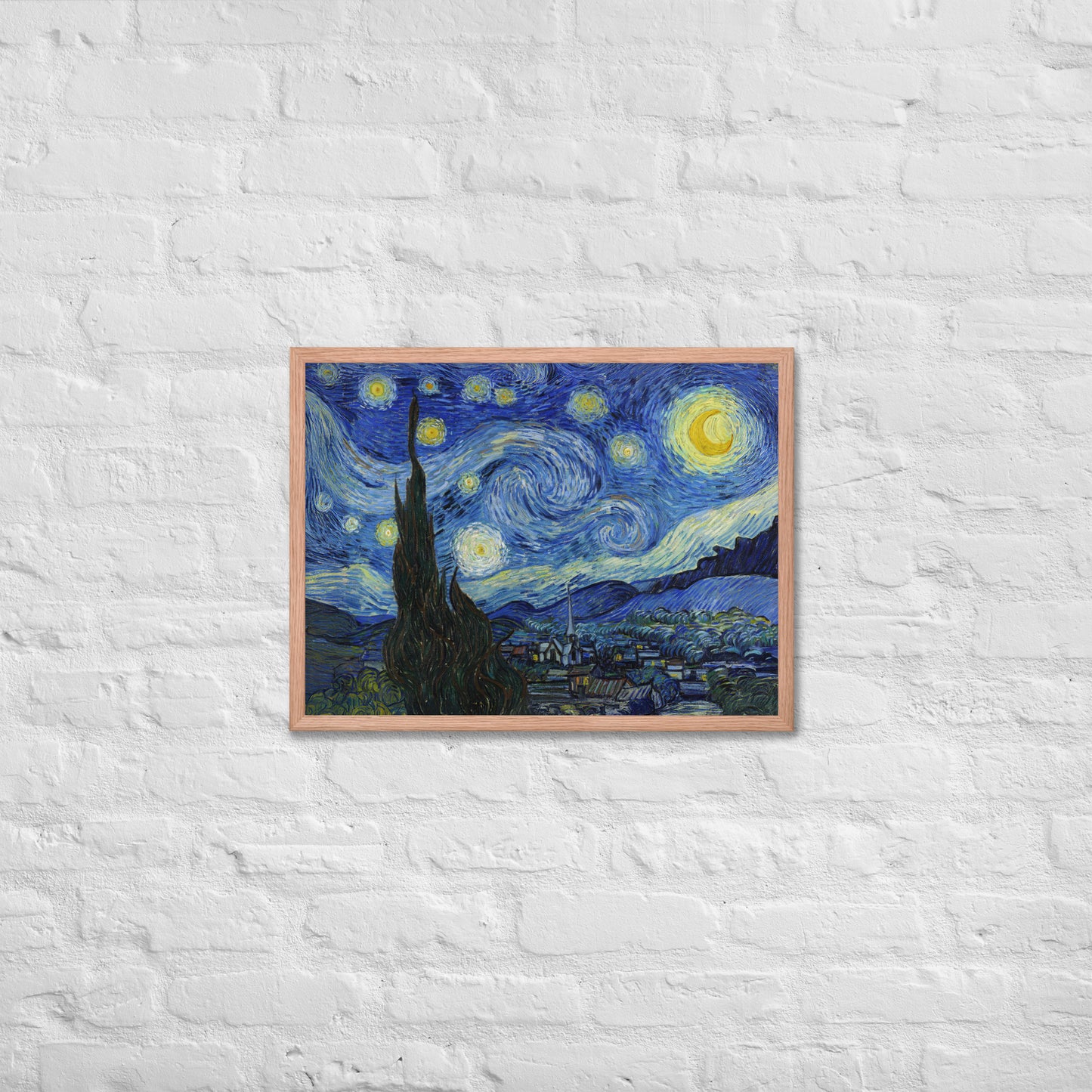 Van Gogh's 'Starry Night' on a 18"x24" red oak framed poster print on a white brick wall.