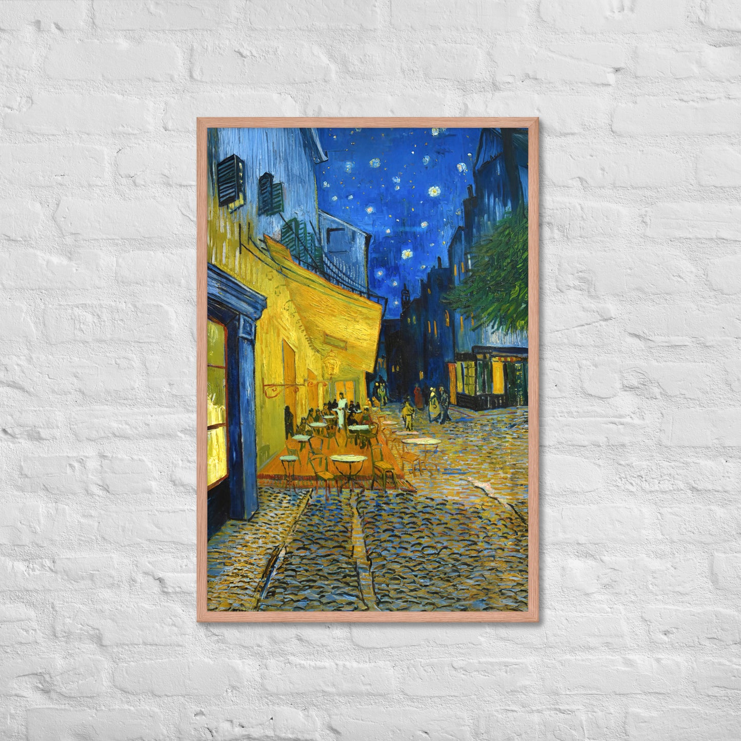 Van Gogh's 'Café Terrace at Night' on a 24"x36" red oak framed poster print on a white brick wall.