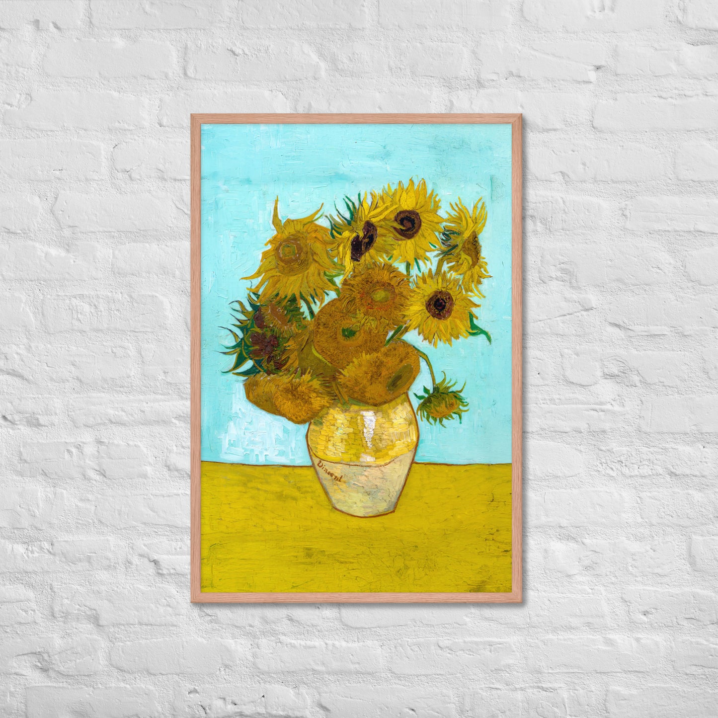 Van Gogh's 'Vase with Twelve Sunflowers' on a 24"x36" red oak framed poster print on a white brick wall.