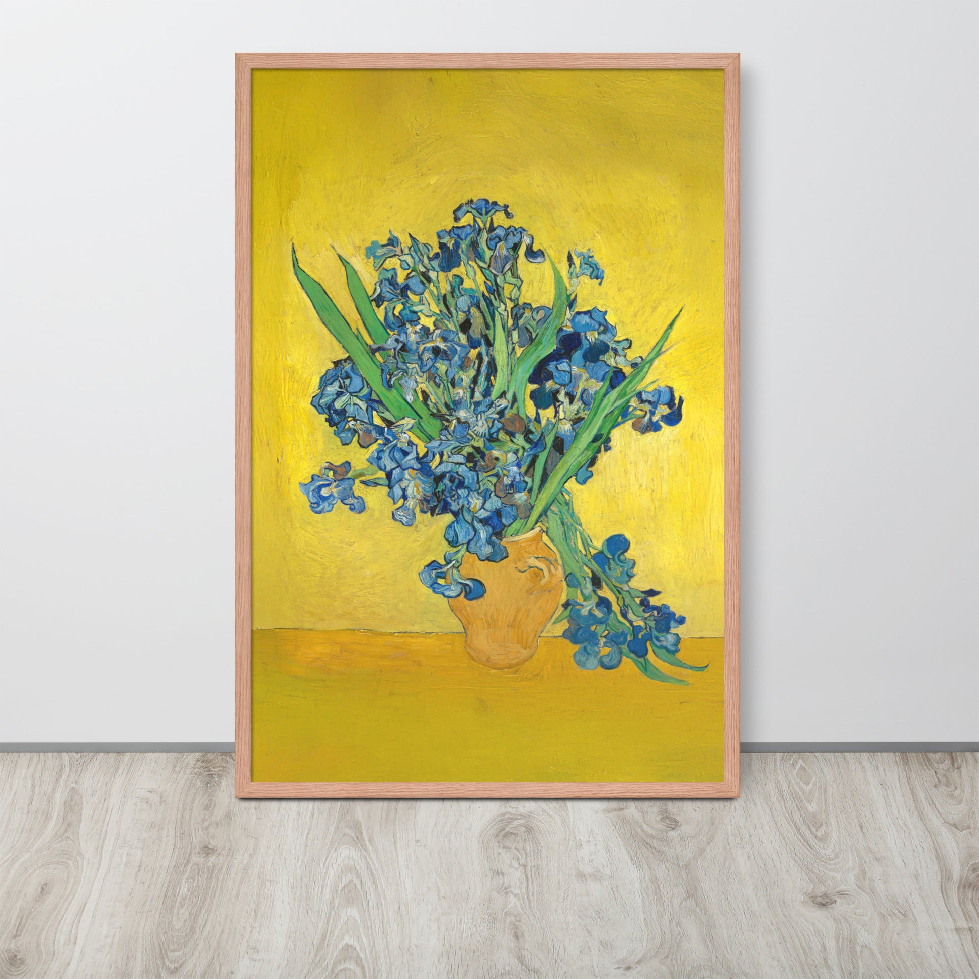 Van Gogh's 'Vase with Irises Against a Yellow Background' on a 24"x36" red oak framed poster print sitting on a wooden floor leaning against a light gray wall.