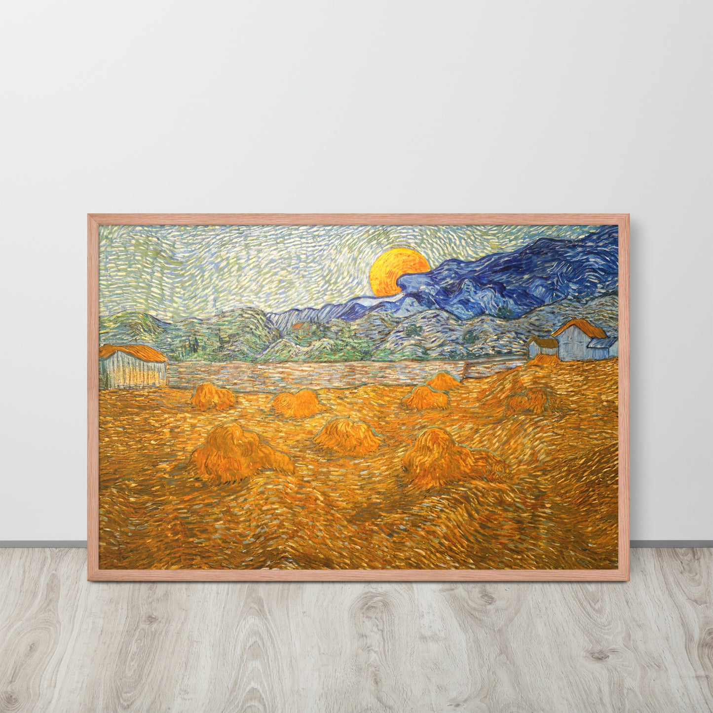 Van Gogh's 'Landscape with Wheat Sheaves and Rising Moon' on a 24"x36" red oak framed poster print sitting on a wooden floor leaning against a light gray wall.