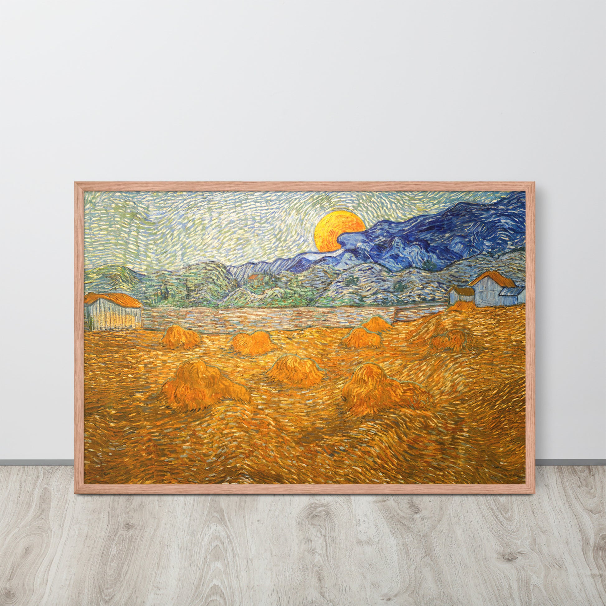 Van Gogh's 'Landscape with Wheat Sheaves and Rising Moon' on a 24"x36" red oak framed poster print sitting on a wooden floor leaning against a light gray wall.