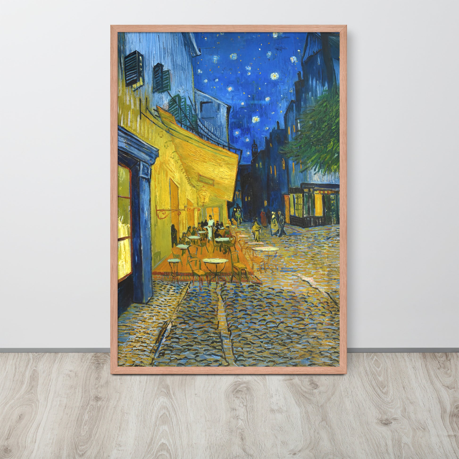 Van Gogh's 'Café Terrace at Night' on a 24"x36" red oak framed poster print sitting on a wooden floor leaning against a light gray wall.