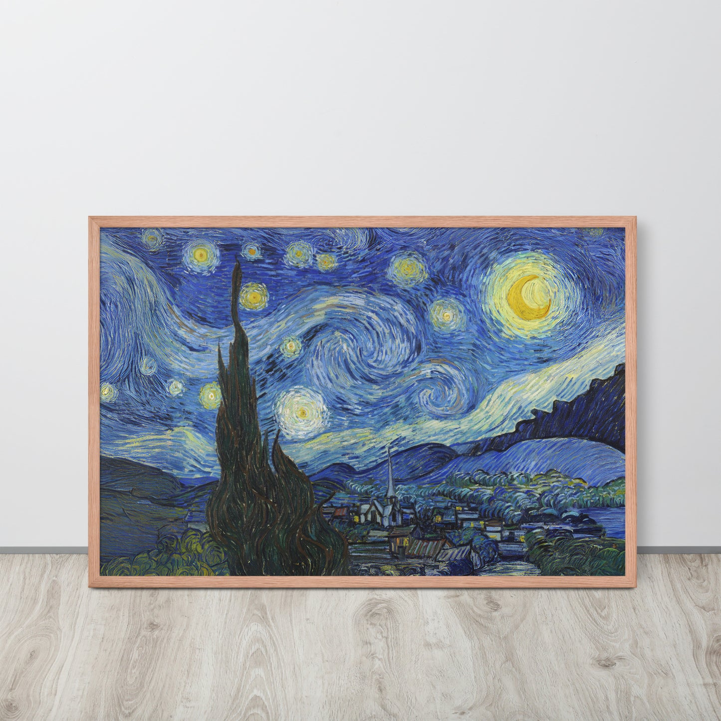 Van Gogh's 'Starry Night' on a 24"x36" red oak framed poster print sitting on a wooden floor leaning against a light gray wall.