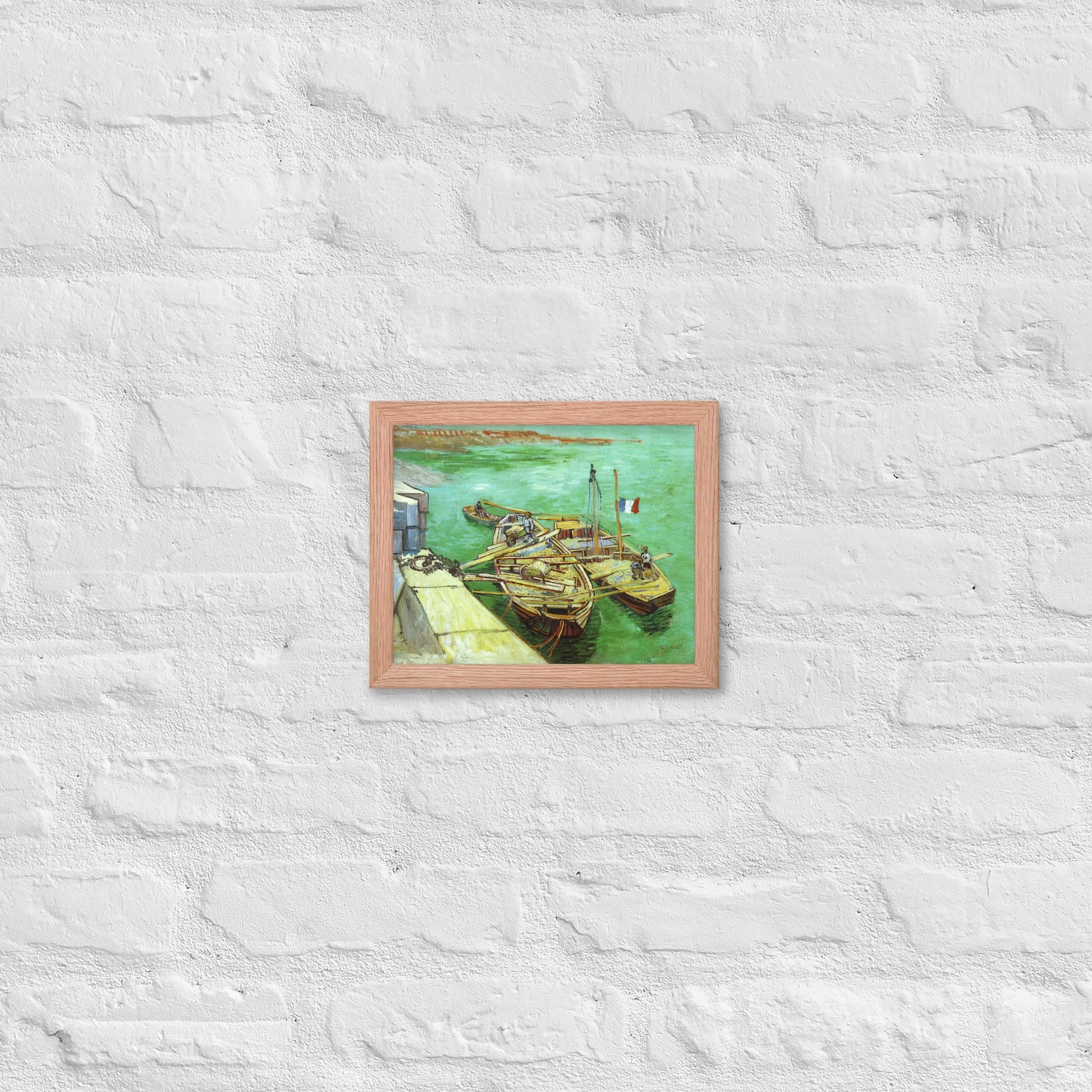 Van Gogh's 'Quay with Men Unloading Sand Barges' on a 8"x10" red oak framed poster print on a white brick wall.