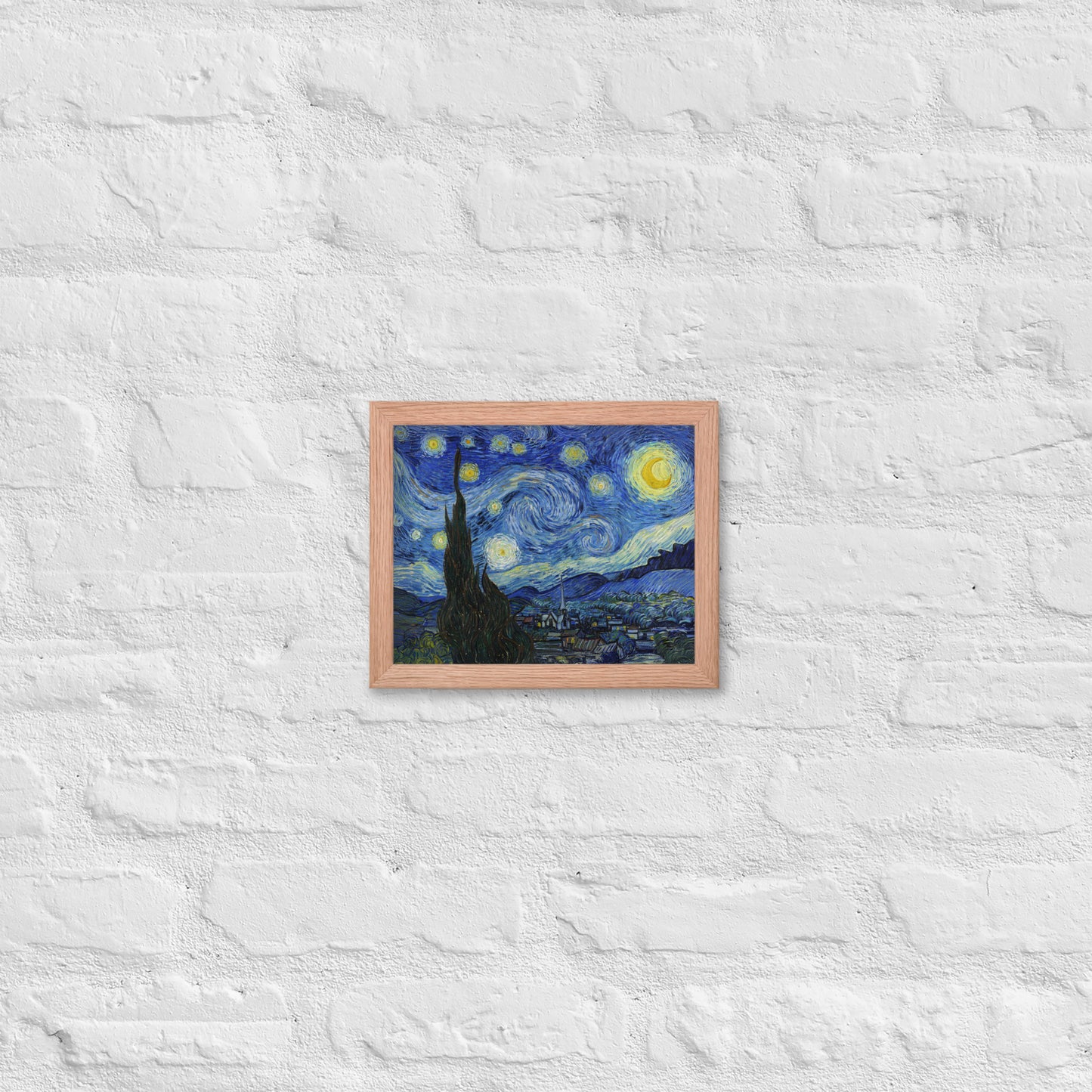 Van Gogh's 'Starry Night' on a 8"x10" red oak framed poster print on a white brick wall.