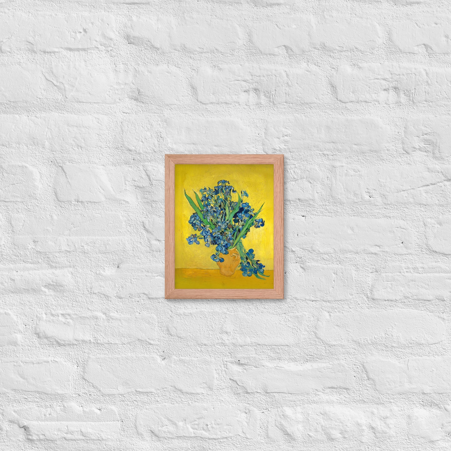 Van Gogh's 'Vase with Irises Against a Yellow Background' on a 8"x10" red oak framed poster print on a white brick wall.