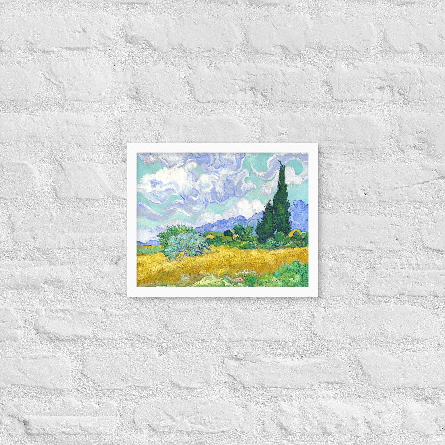 Van Gogh's 'Wheat Field with Cypresses' on a 11"x14" white framed poster print on a white brick wall.