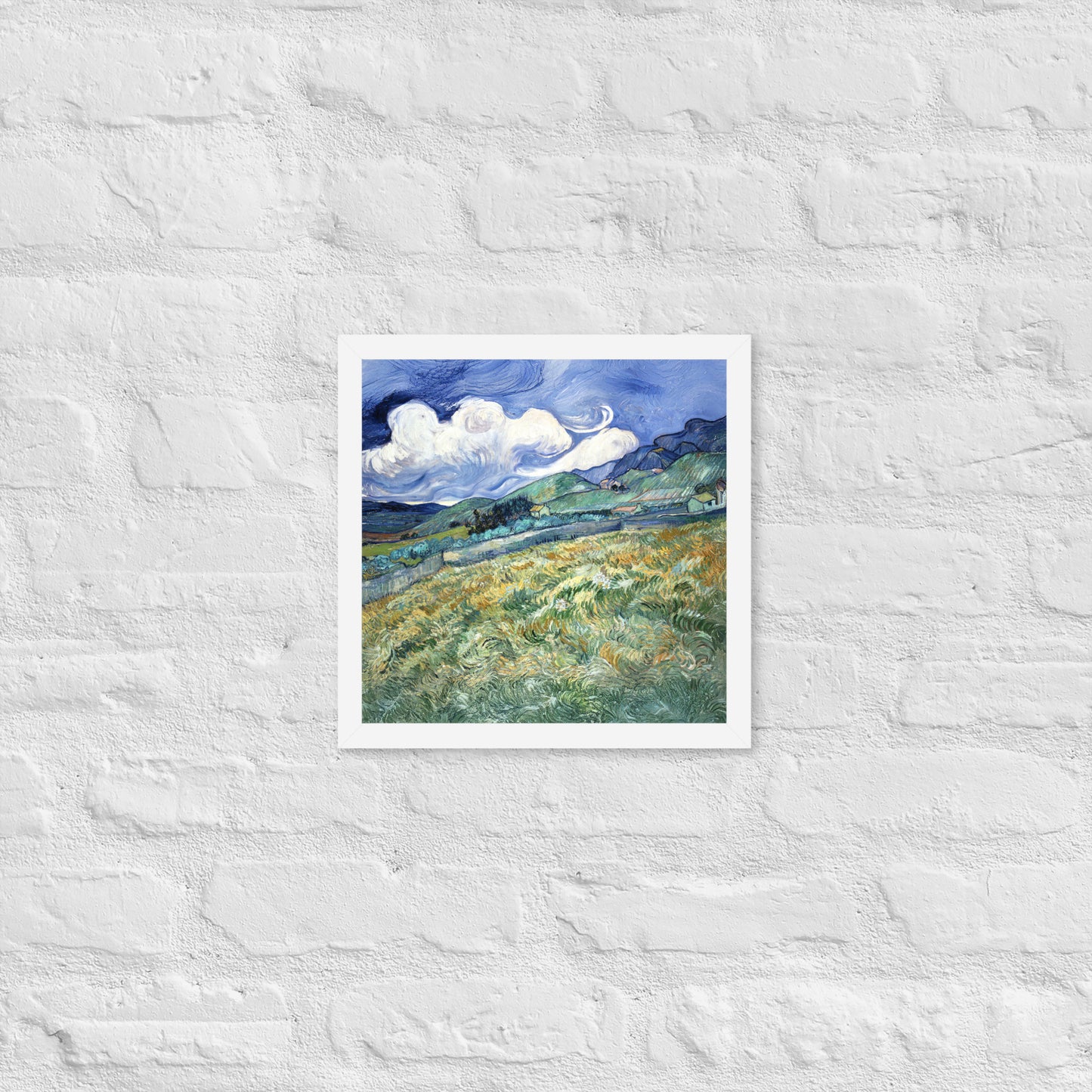Van Gogh's 'Landscape from Saint-Rémy' on a 12"x12" white framed poster print on a white brick wall.