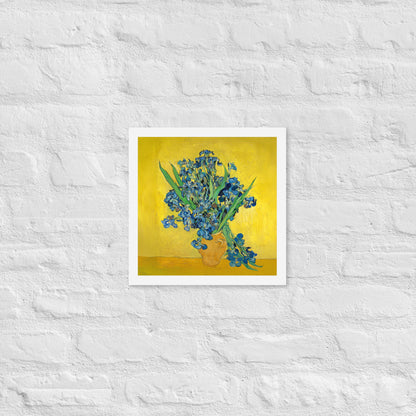 Van Gogh's 'Vase with Irises Against a Yellow Background' on a 12"x12" white framed poster print on a white brick wall.