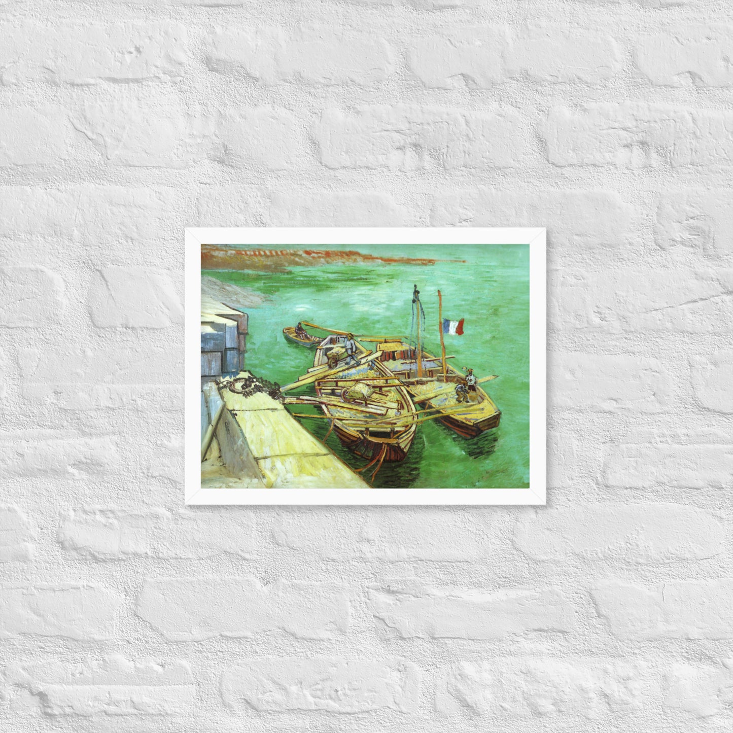 Van Gogh's 'Quay with Men Unloading Sand Barges' on a 12"x16" white framed poster print on a white brick wall.