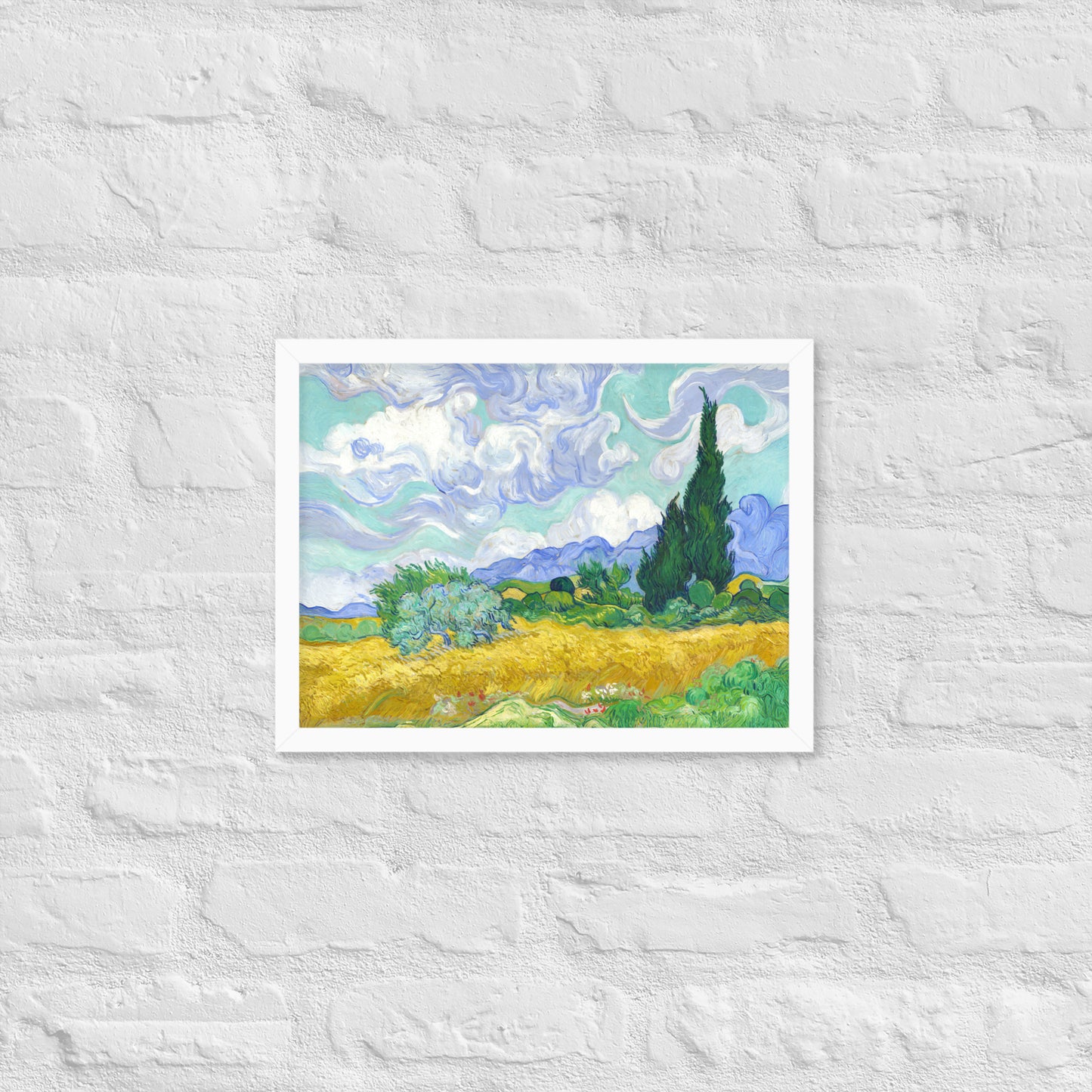 Van Gogh's 'Wheat Field with Cypresses' on a 12"x16" white framed poster print on a white brick wall.