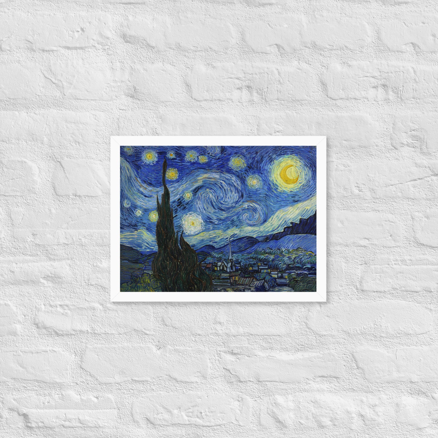 Van Gogh's 'Starry Night' on a 12"x16" white framed poster print on a white brick wall.