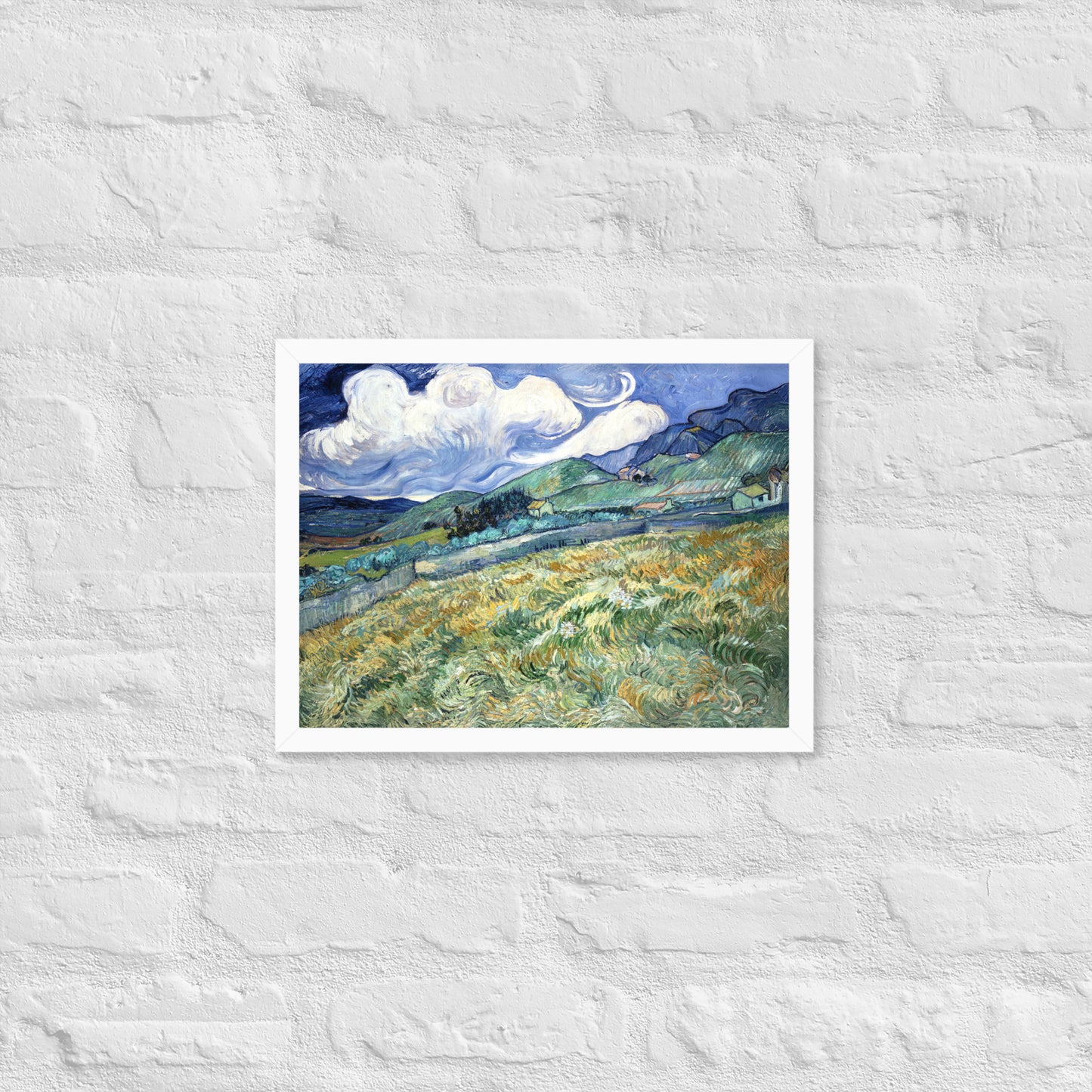 Van Gogh's 'Landscape from Saint-Rémy' on a 12"x16" white framed poster print on a white brick wall.