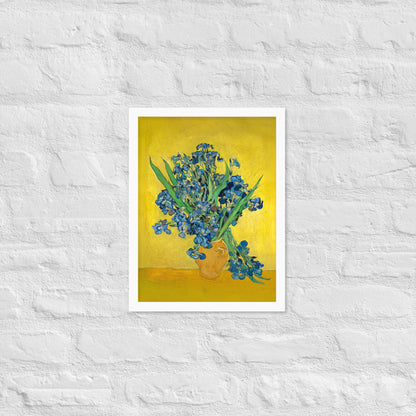 Van Gogh's 'Vase with Irises Against a Yellow Background' on a 12"x16" white framed poster print on a white brick wall.