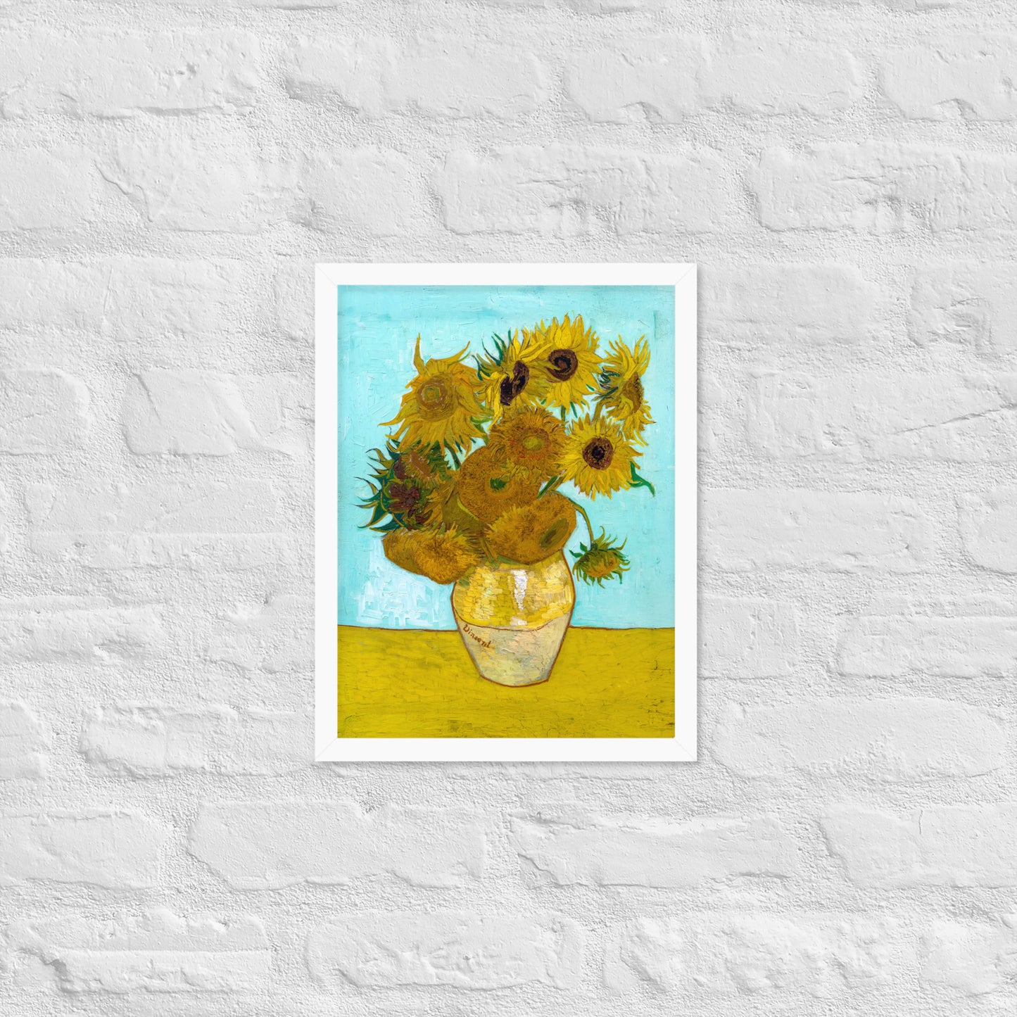 Van Gogh's 'Vase with Twelve Sunflowers' on a 12"x16" white framed poster print on a white brick wall.
