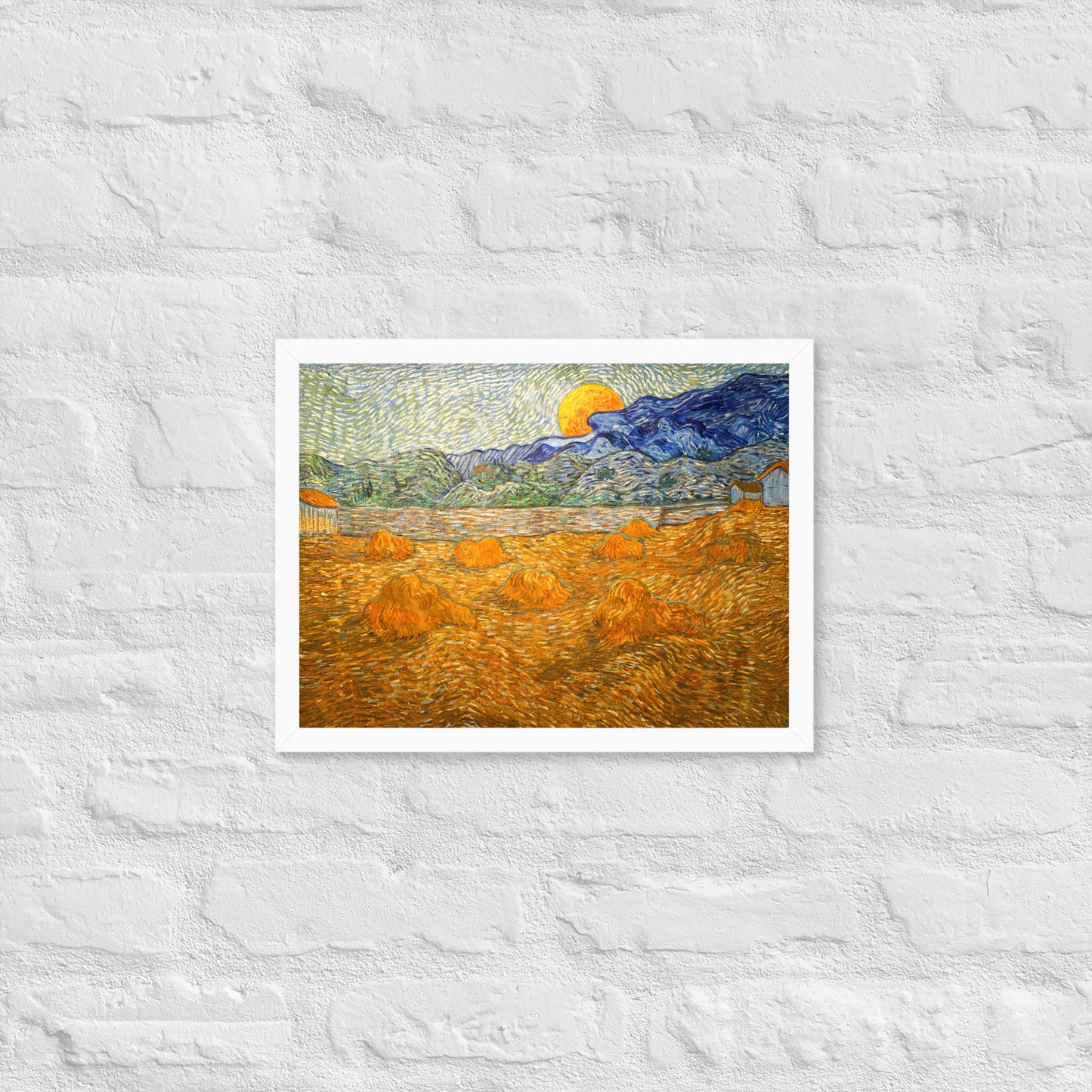 Van Gogh's 'Landscape with Wheat Sheaves and Rising Moon' on a 12"x16" white framed poster print on a white brick wall.